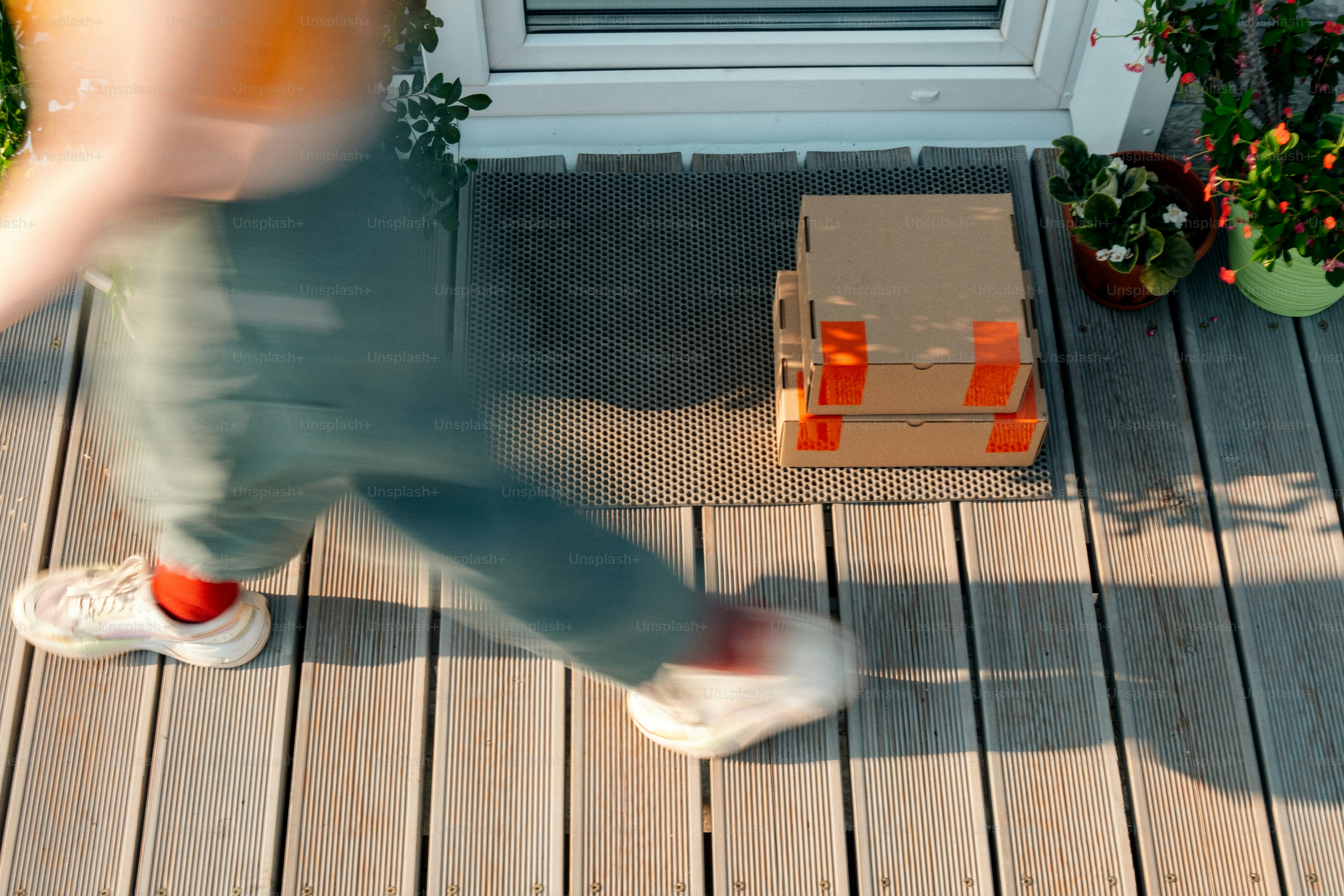 Blurred person walking past stacked packages on sunny porch