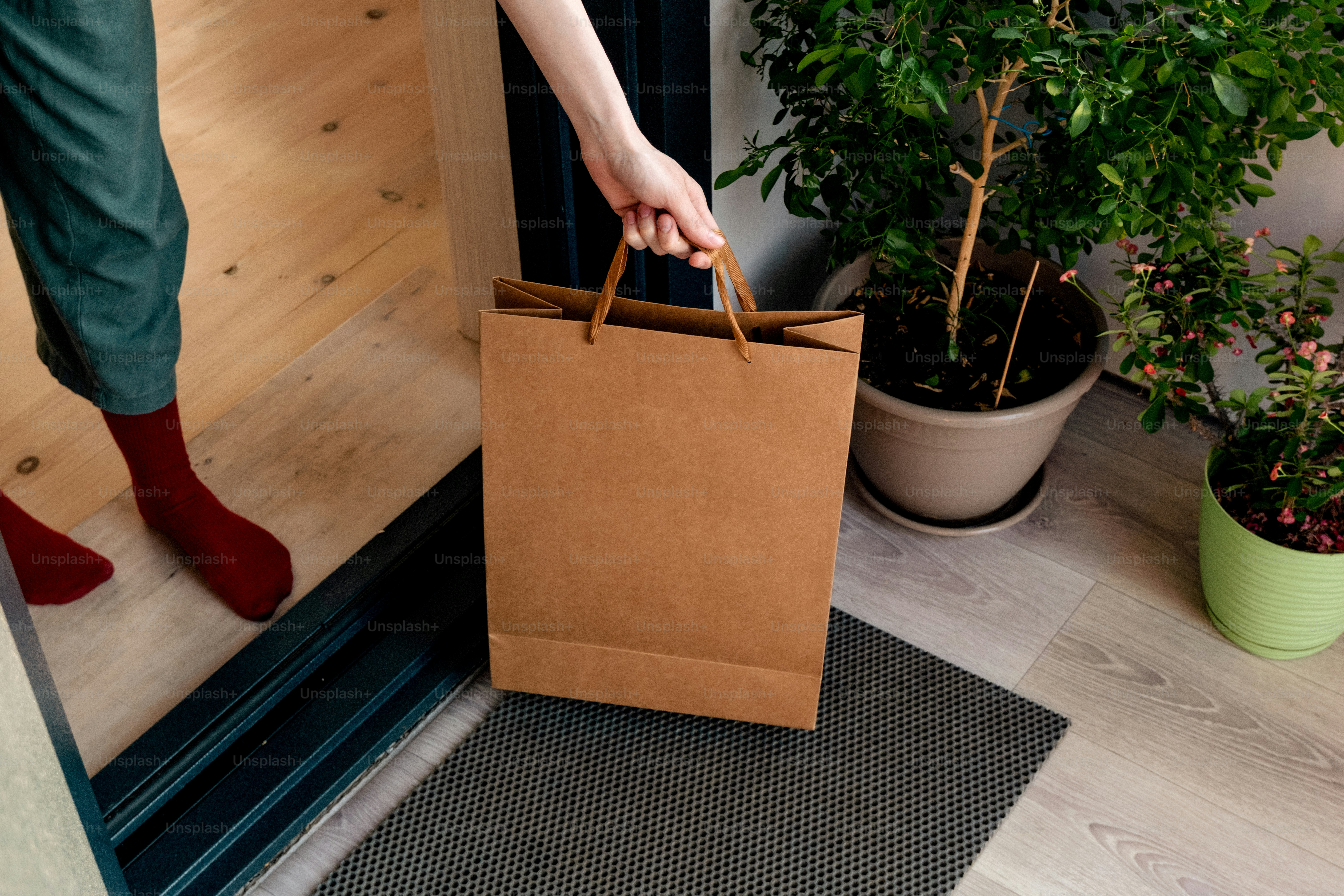 Hand reaching for brown paper bag on doorstep