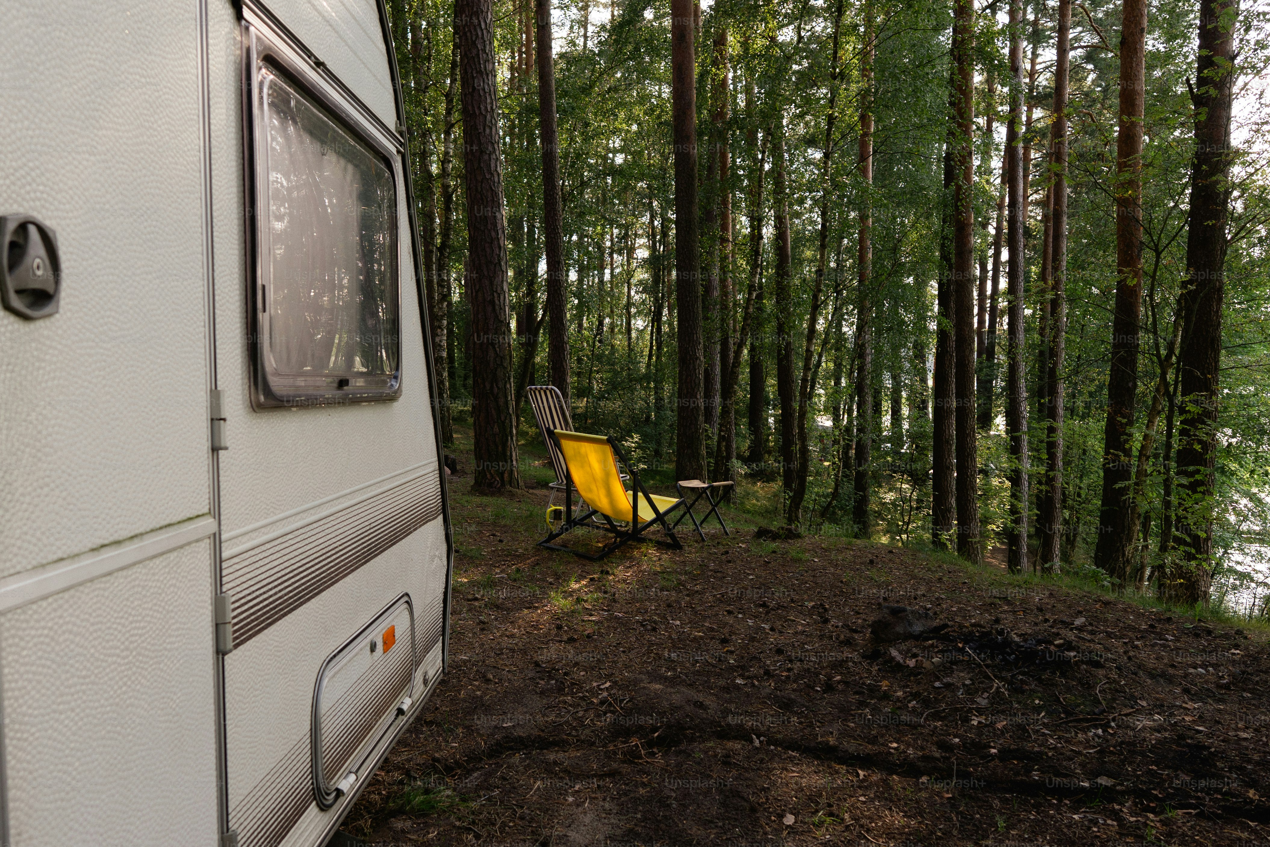 Caravan parked in a forest near a lake