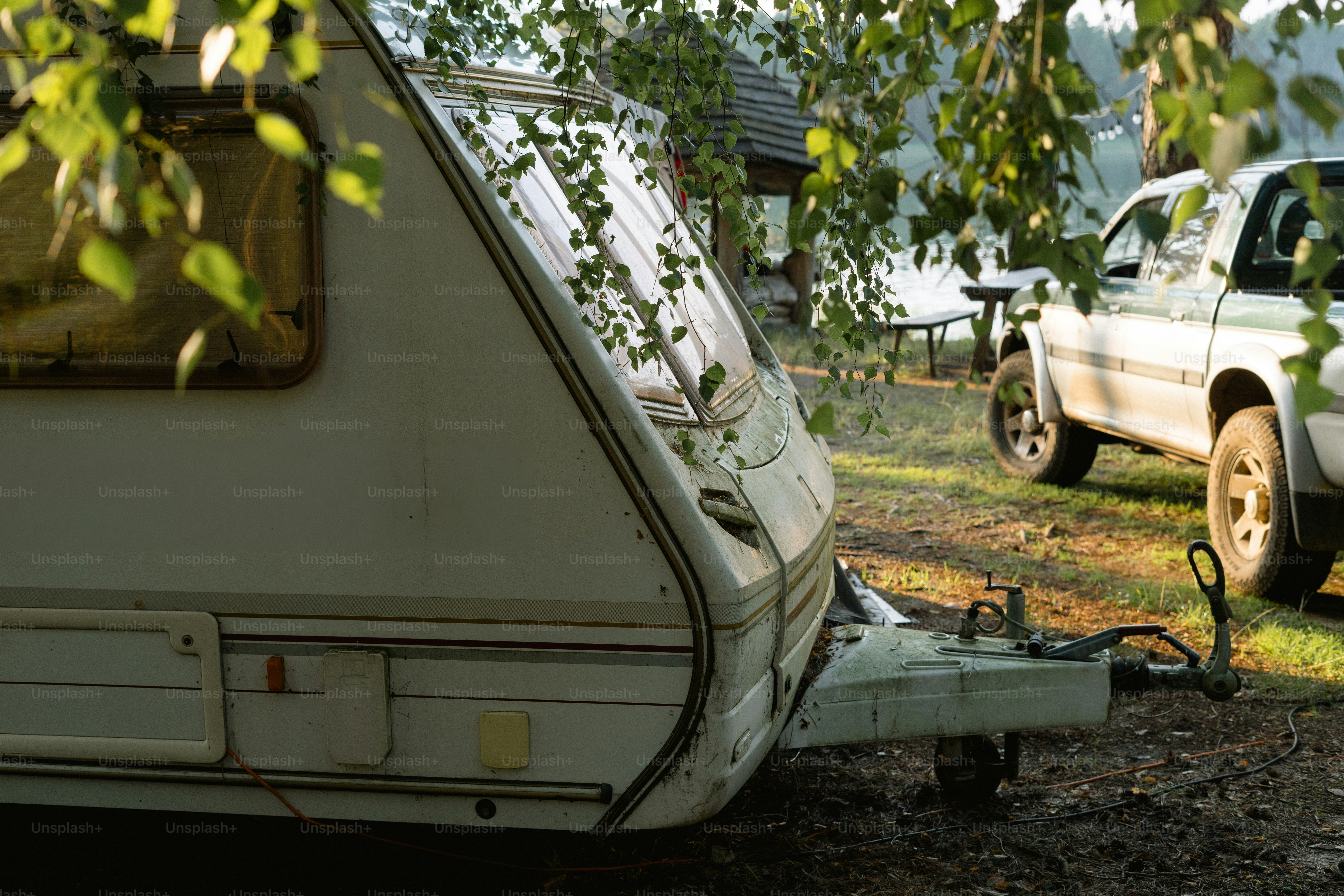 White caravan and pickup truck in dappled light