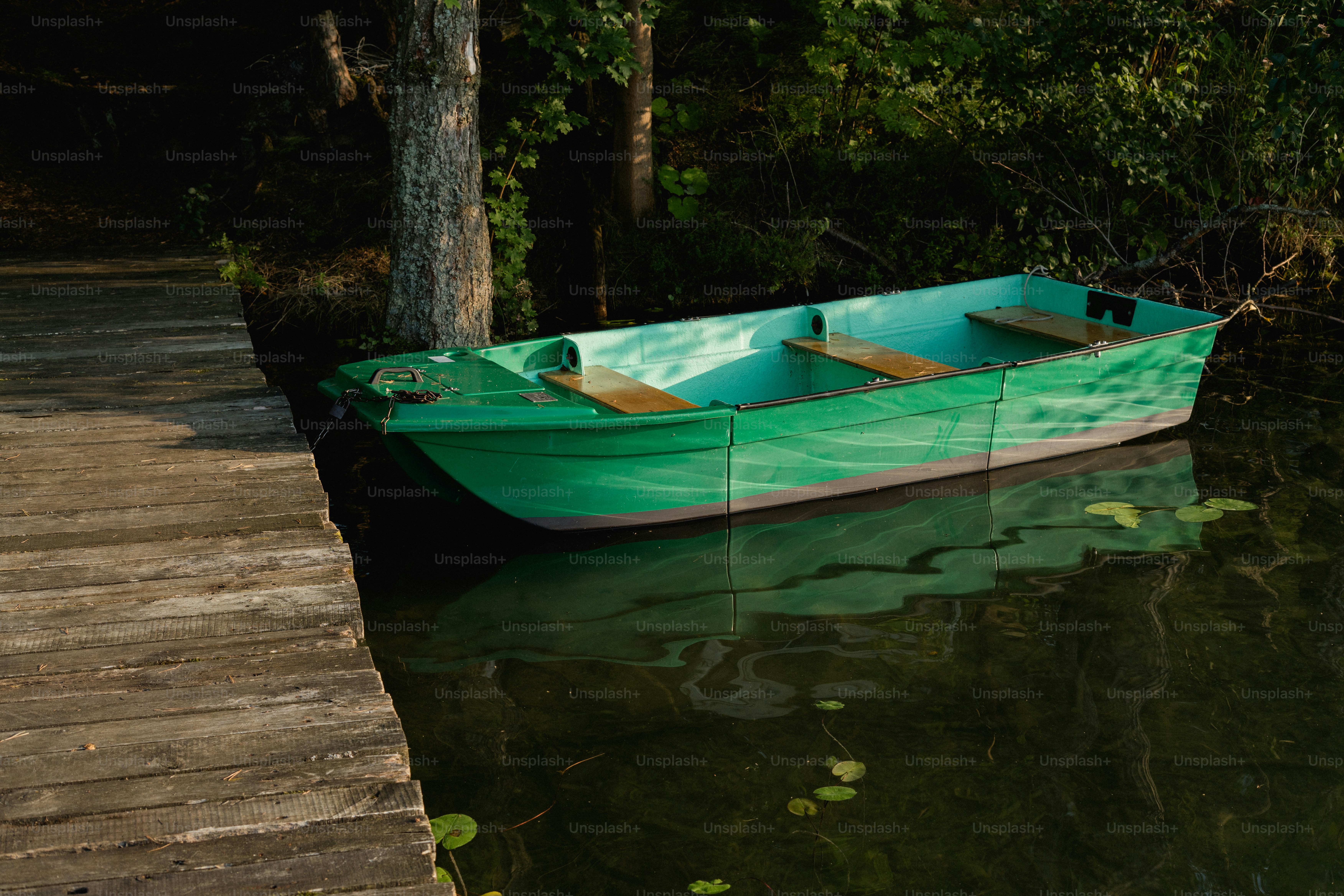 Green rowboat moored at wooden pier