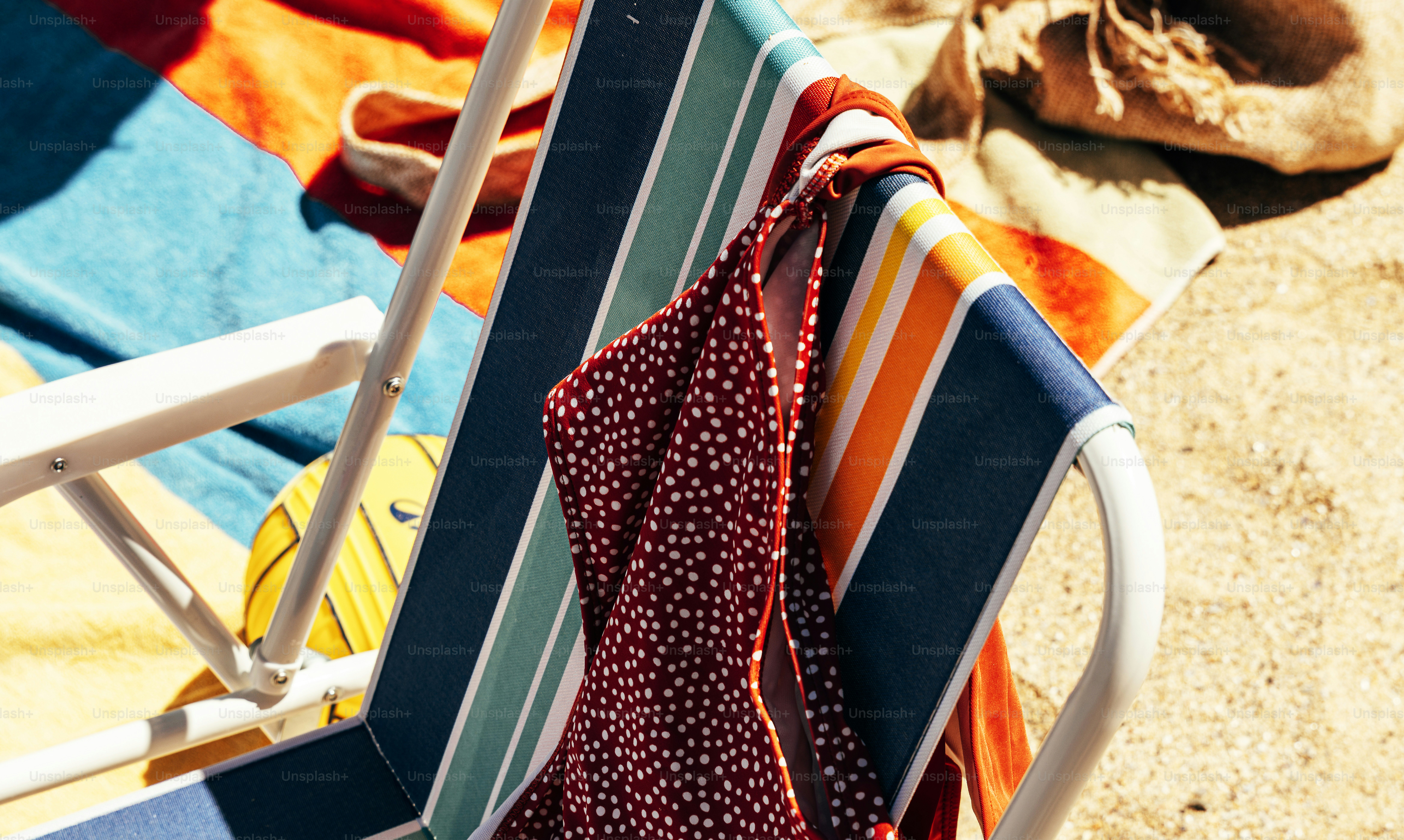 Striped beach chair, swimsuit, and towel on sand