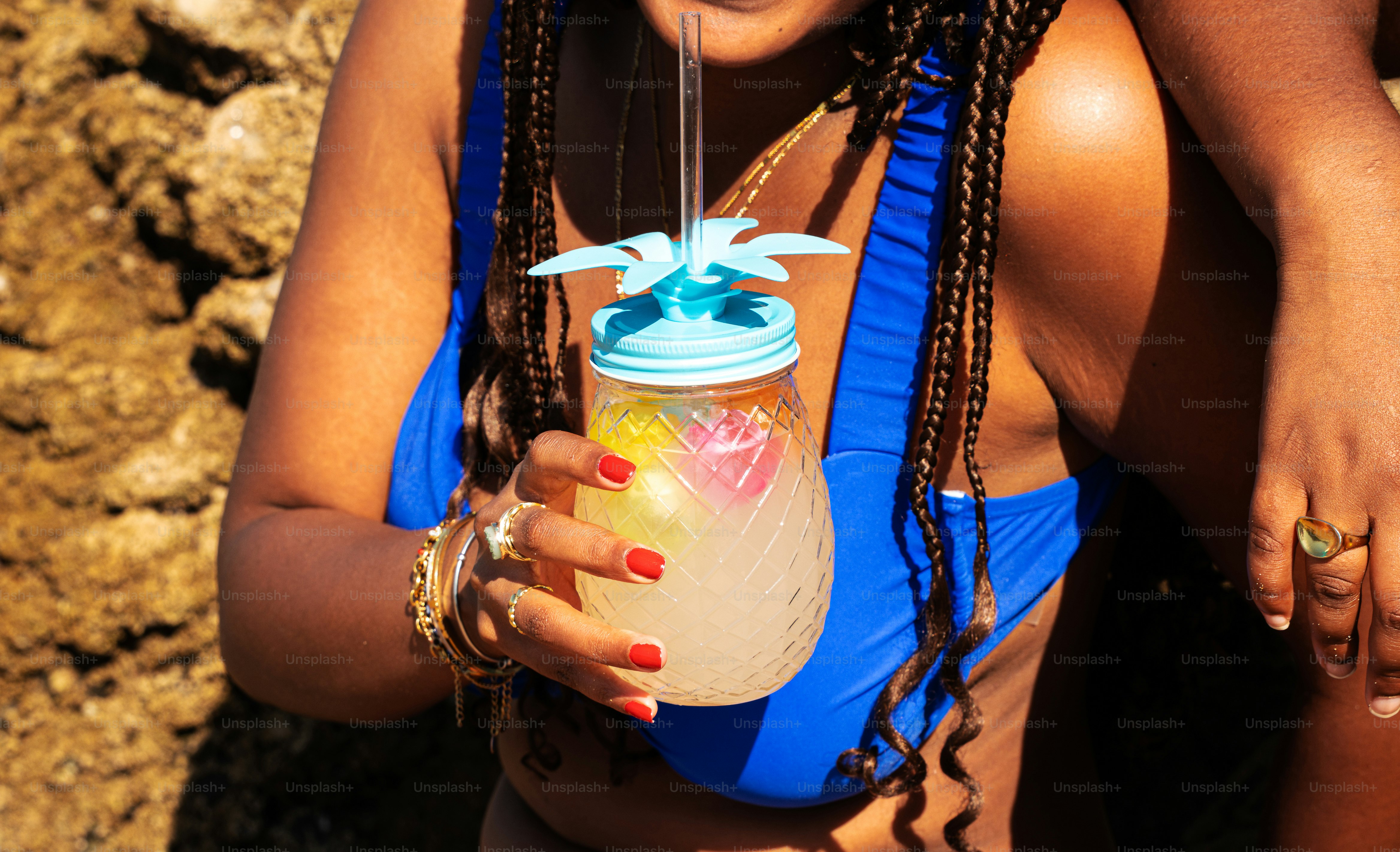Woman in blue swimsuit holding pineapple drink