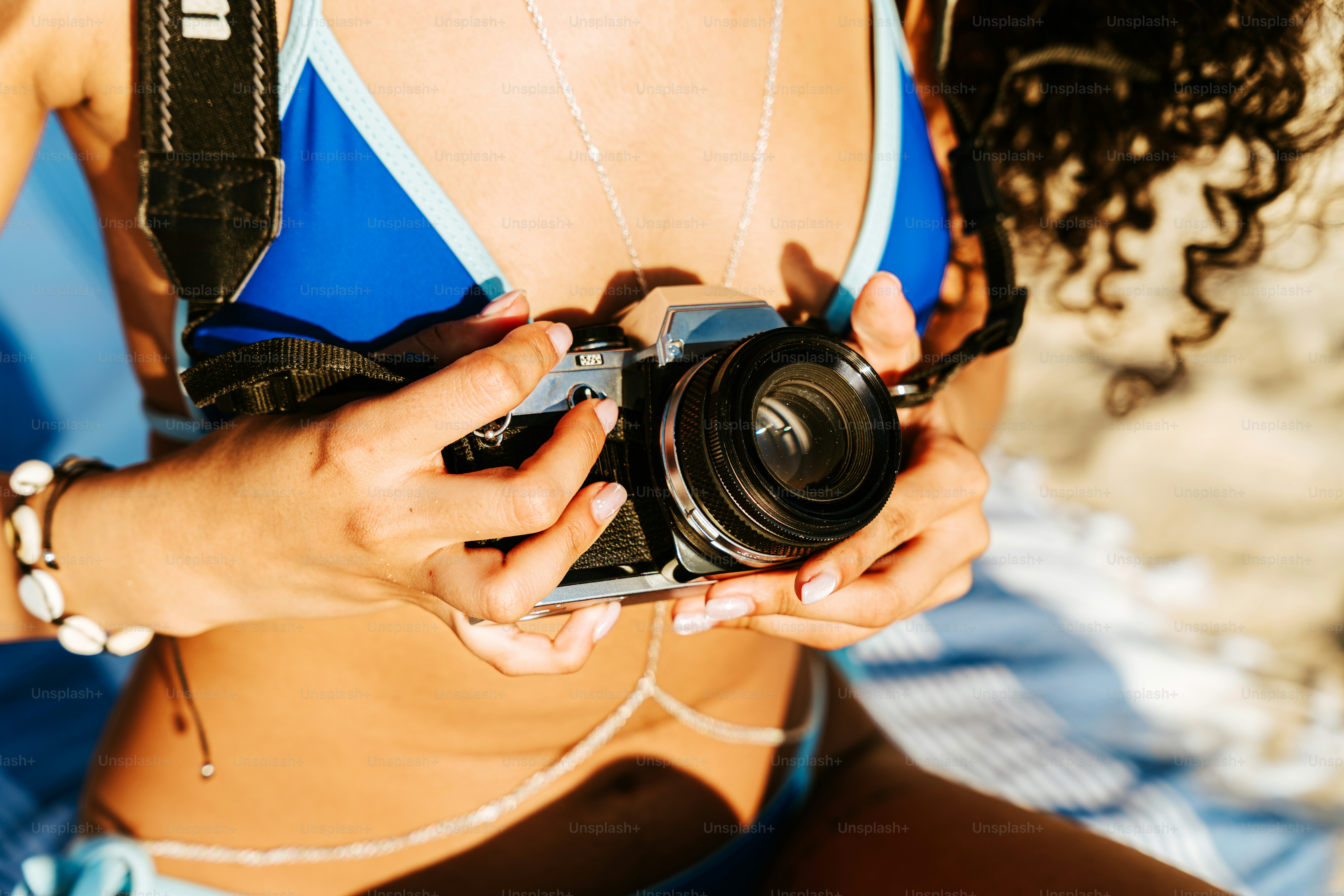 Woman in blue bikini holding retro camera on beach