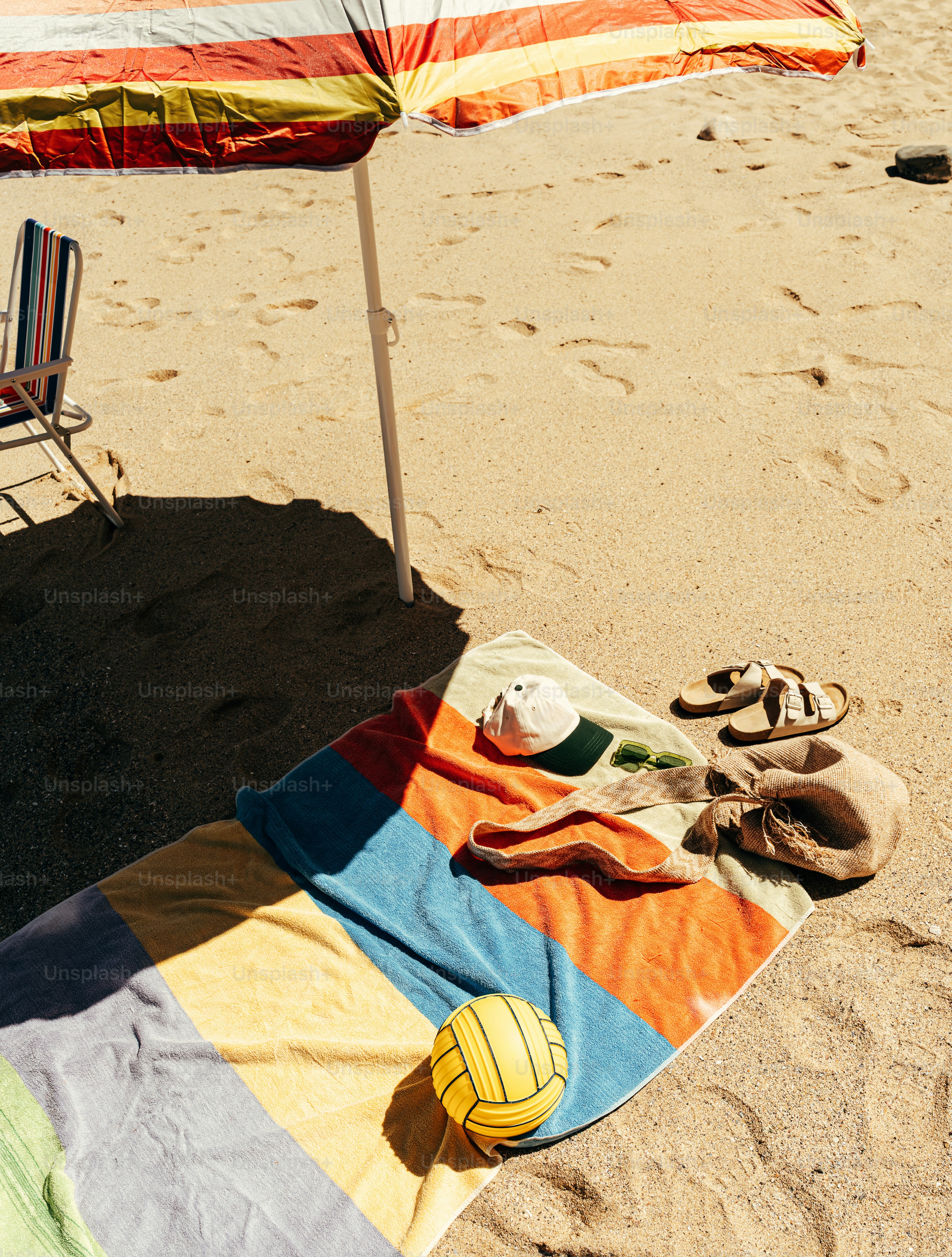 Colorful beach umbrella, towel, and volleyball on sand