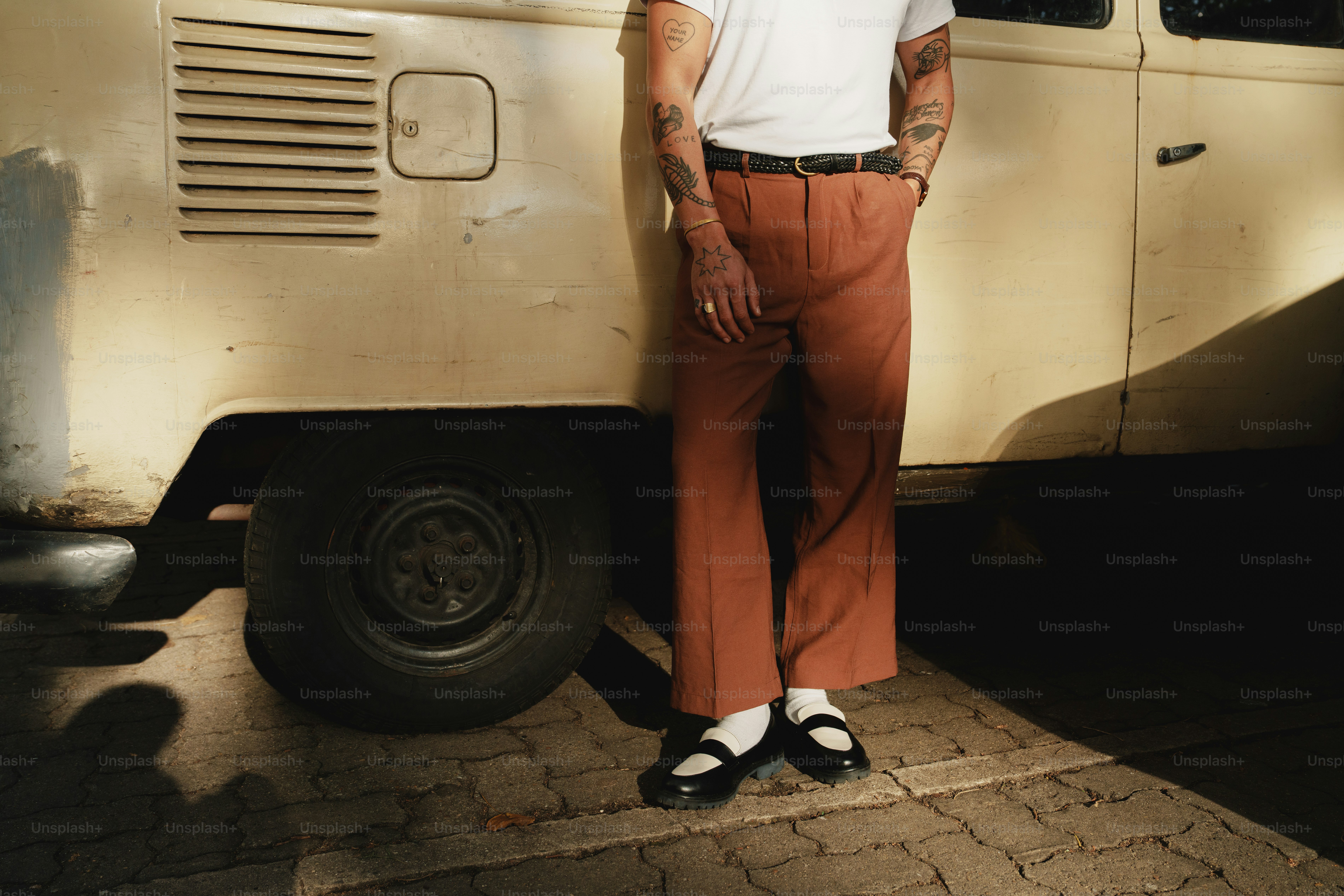Person in ausgestellten Hosen, die sich an einen Vintage-Van lehnt