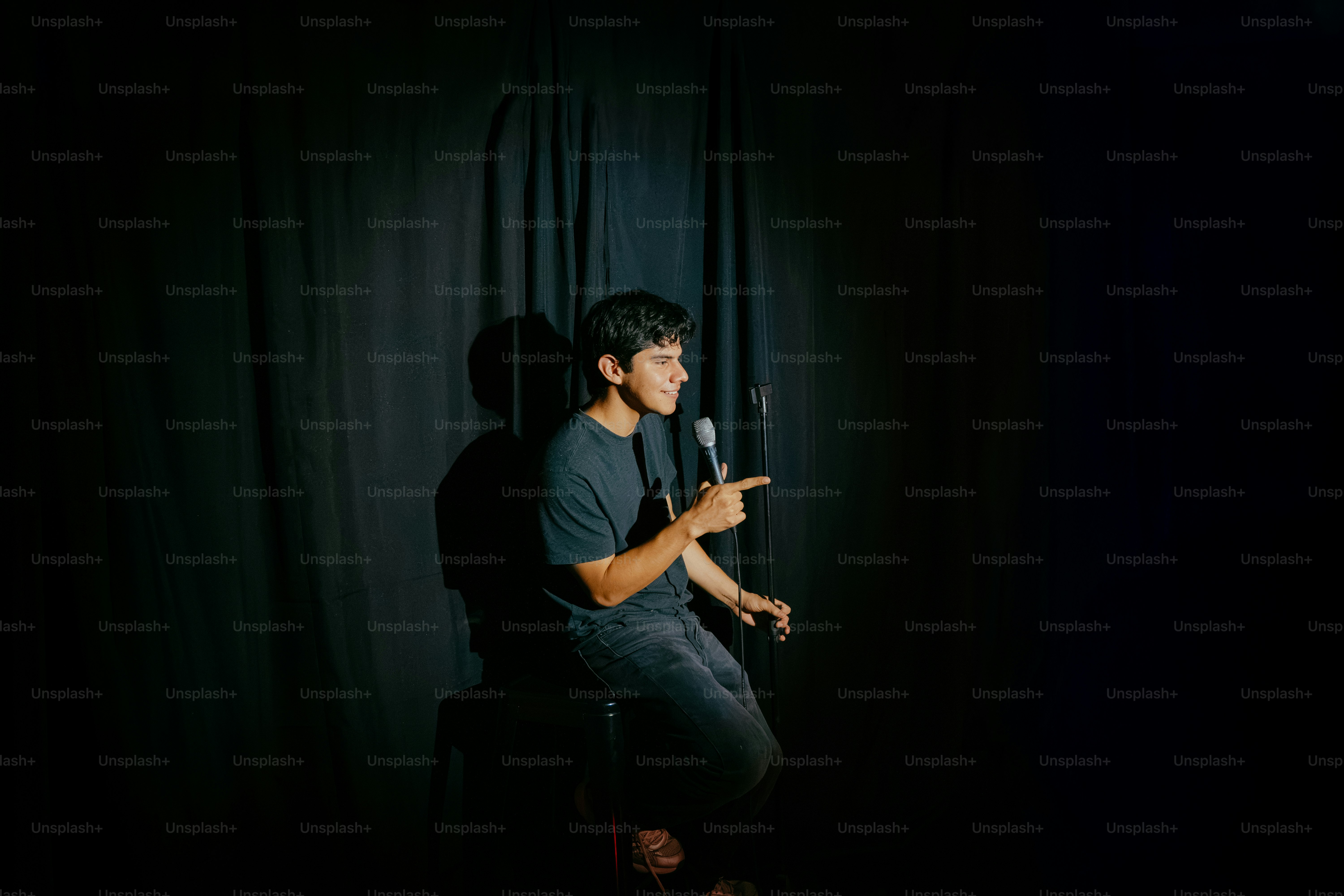 Man on stage holding microphone, pointing