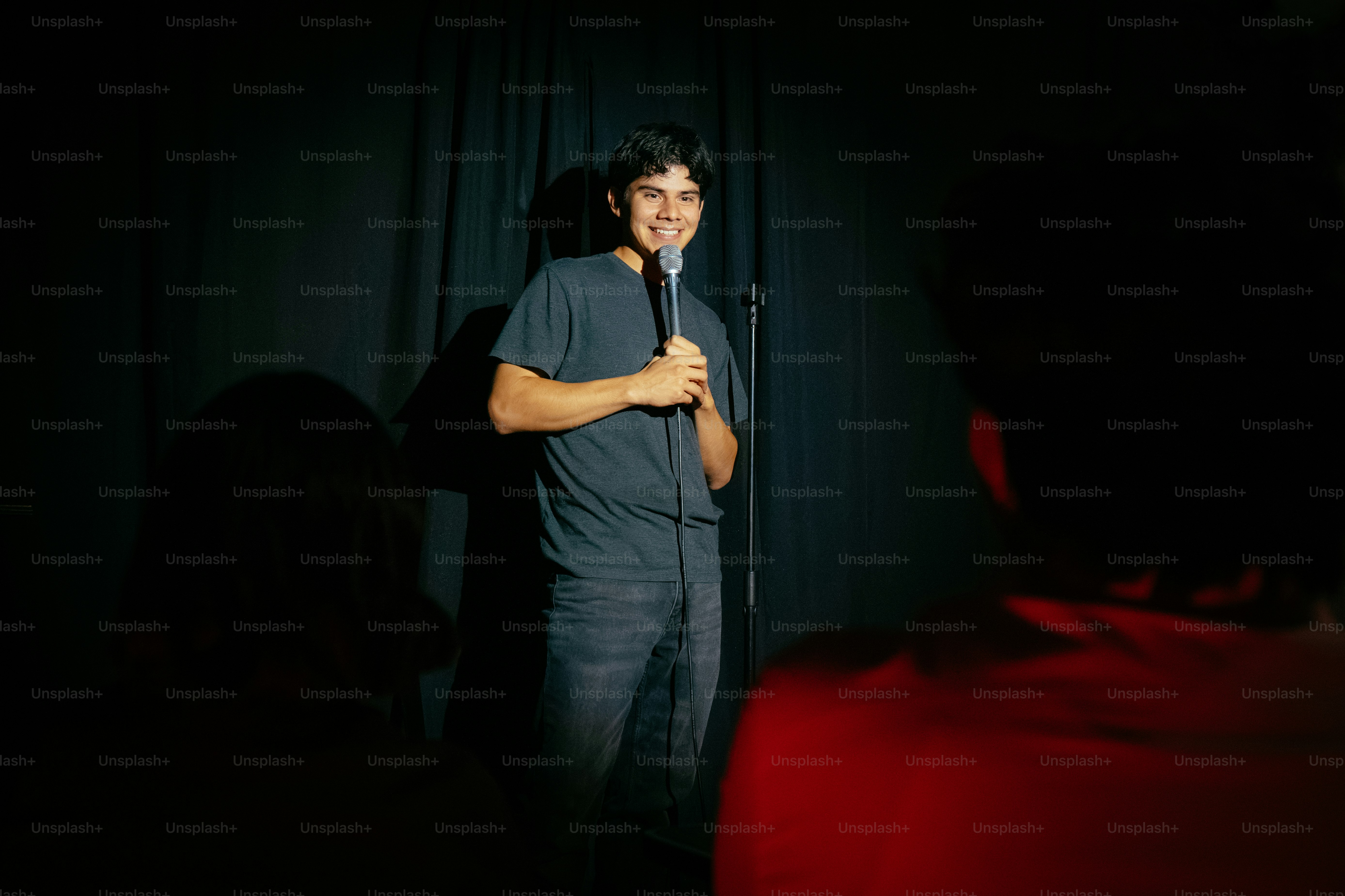 Comedian performing stand-up with microphone on dark stage