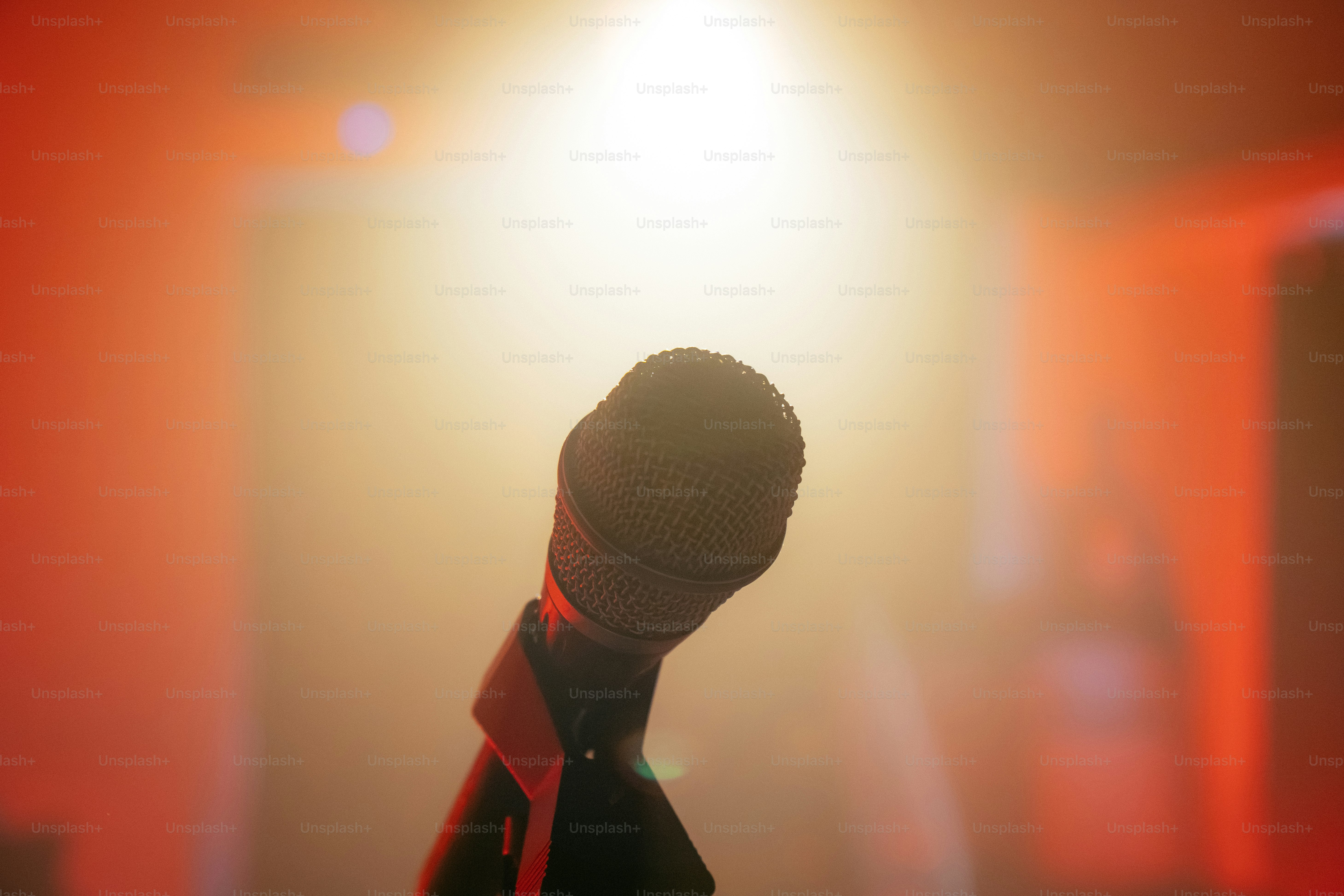 Microphone on stage under bright spotlight, red glow