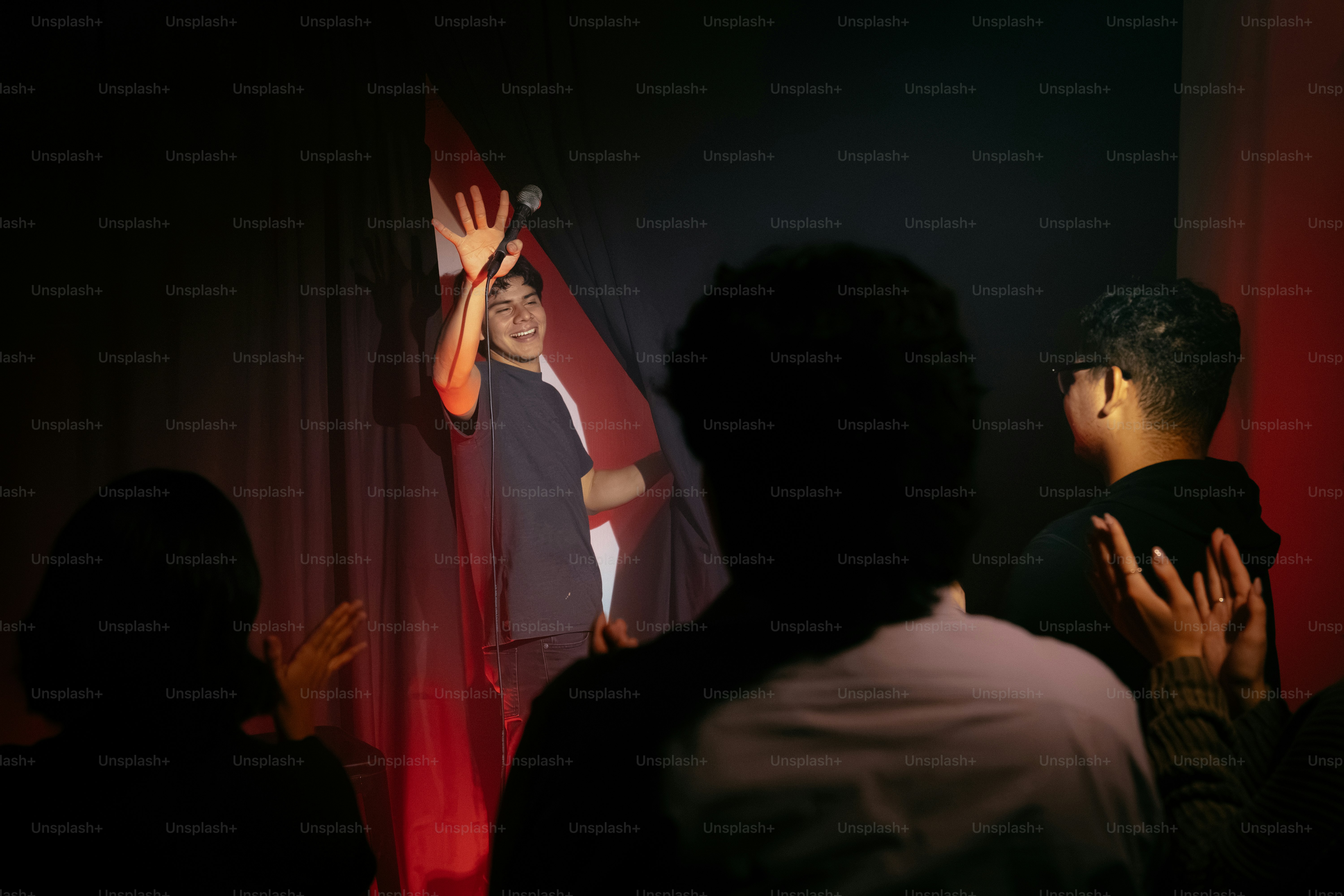Man waving on stage to an applauding audience
