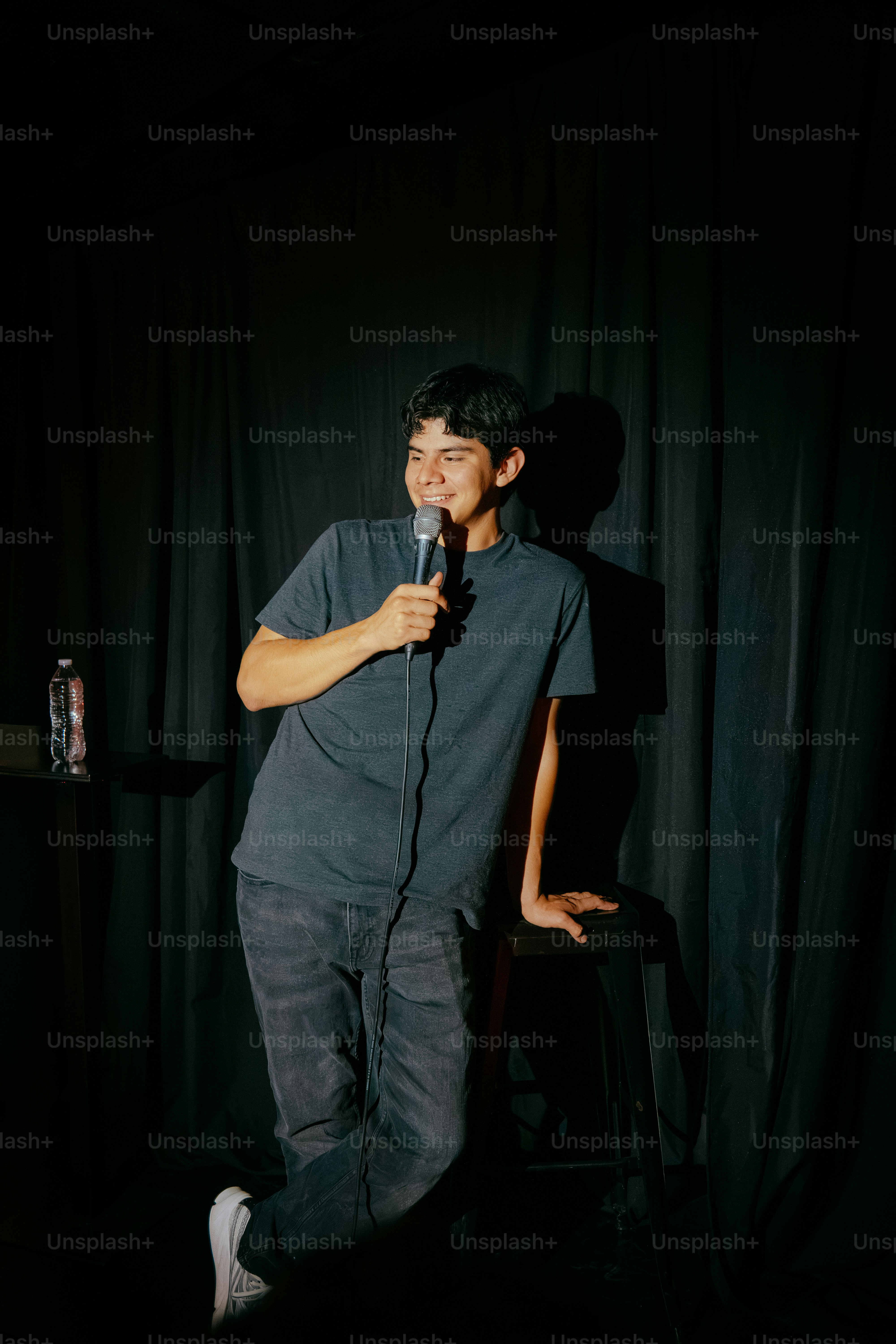 Young man performing with microphone on dark stage