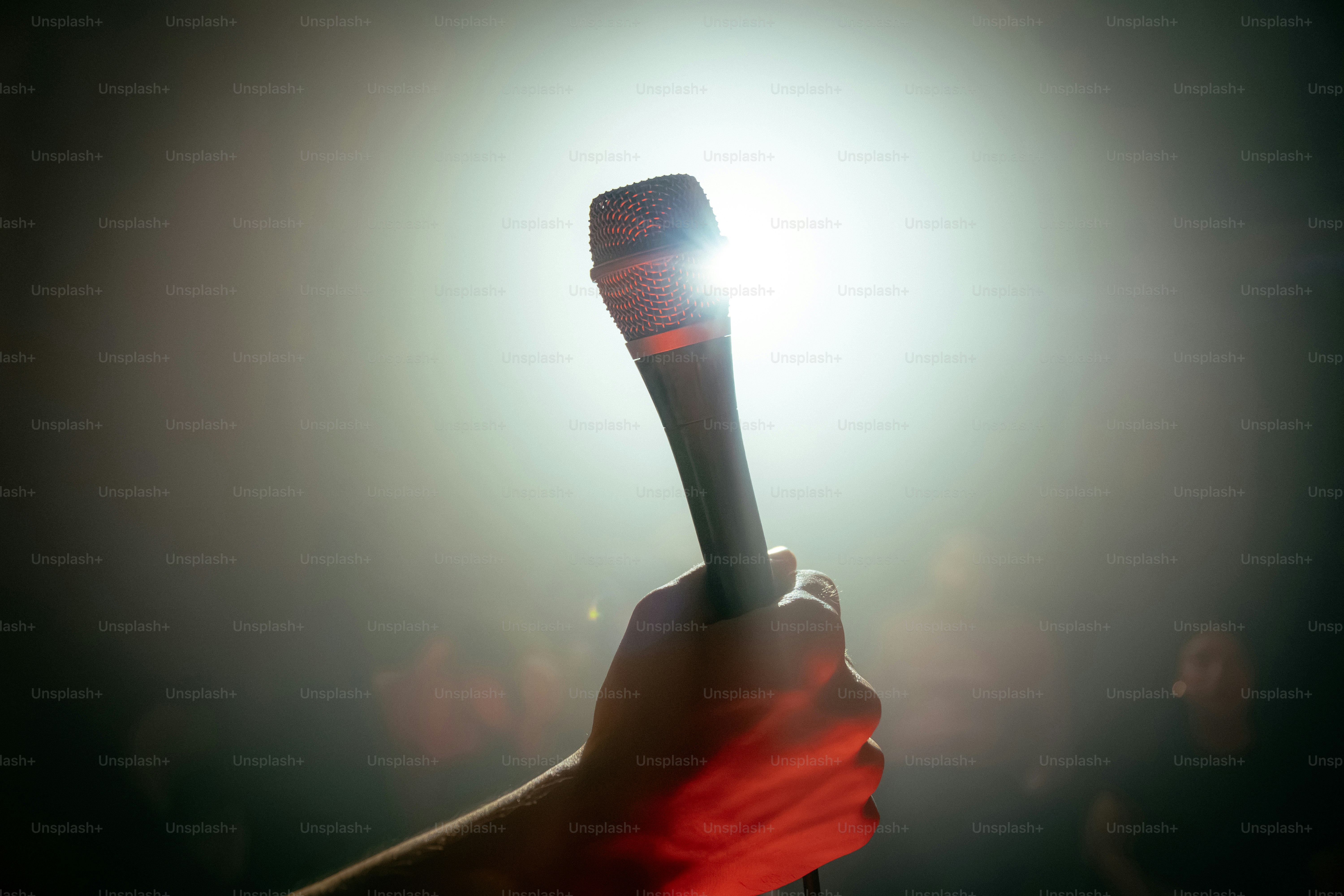 Hand holding microphone under bright spotlight