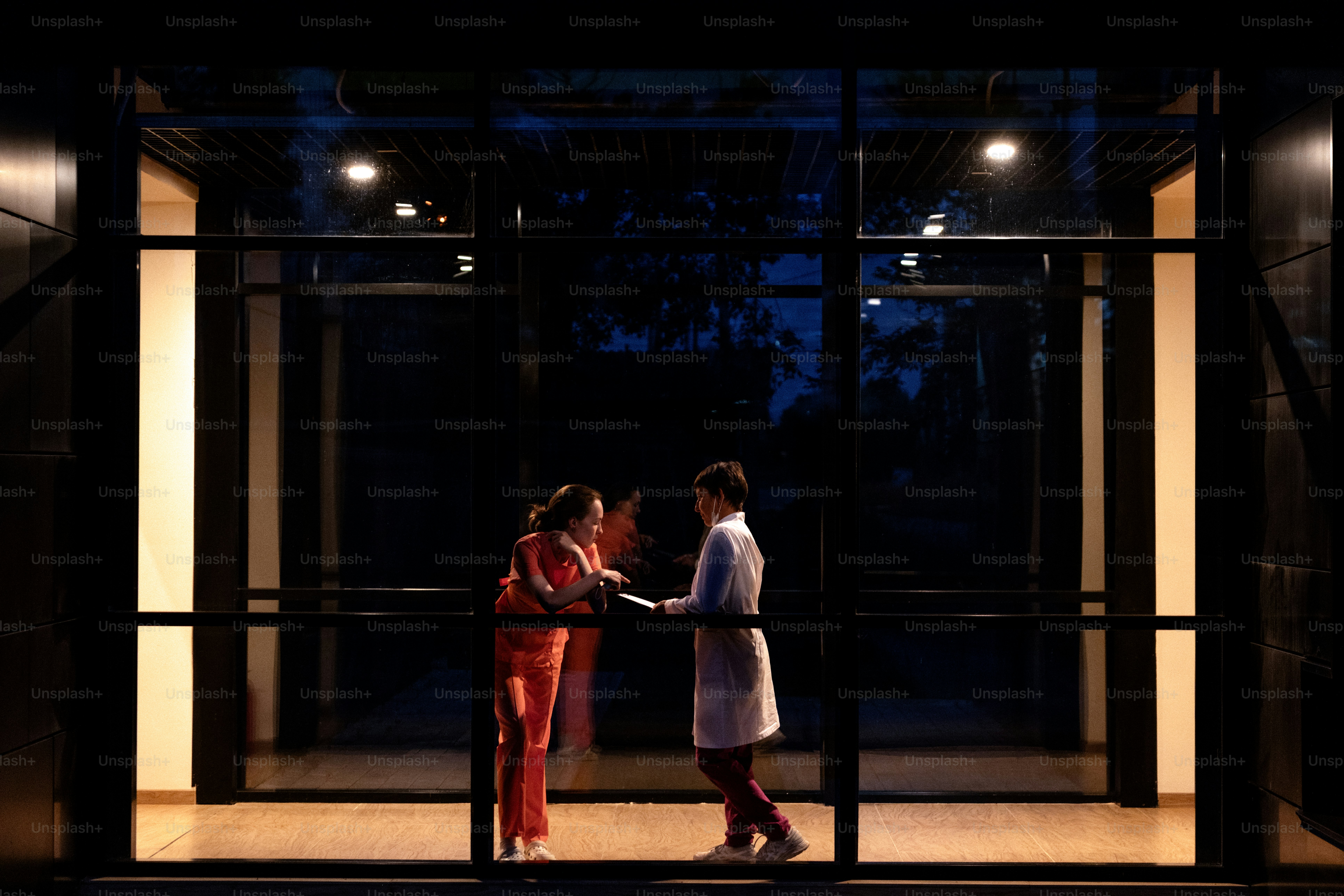 People in lab coat and jumpsuit exchanging item at night photo – Work ...
