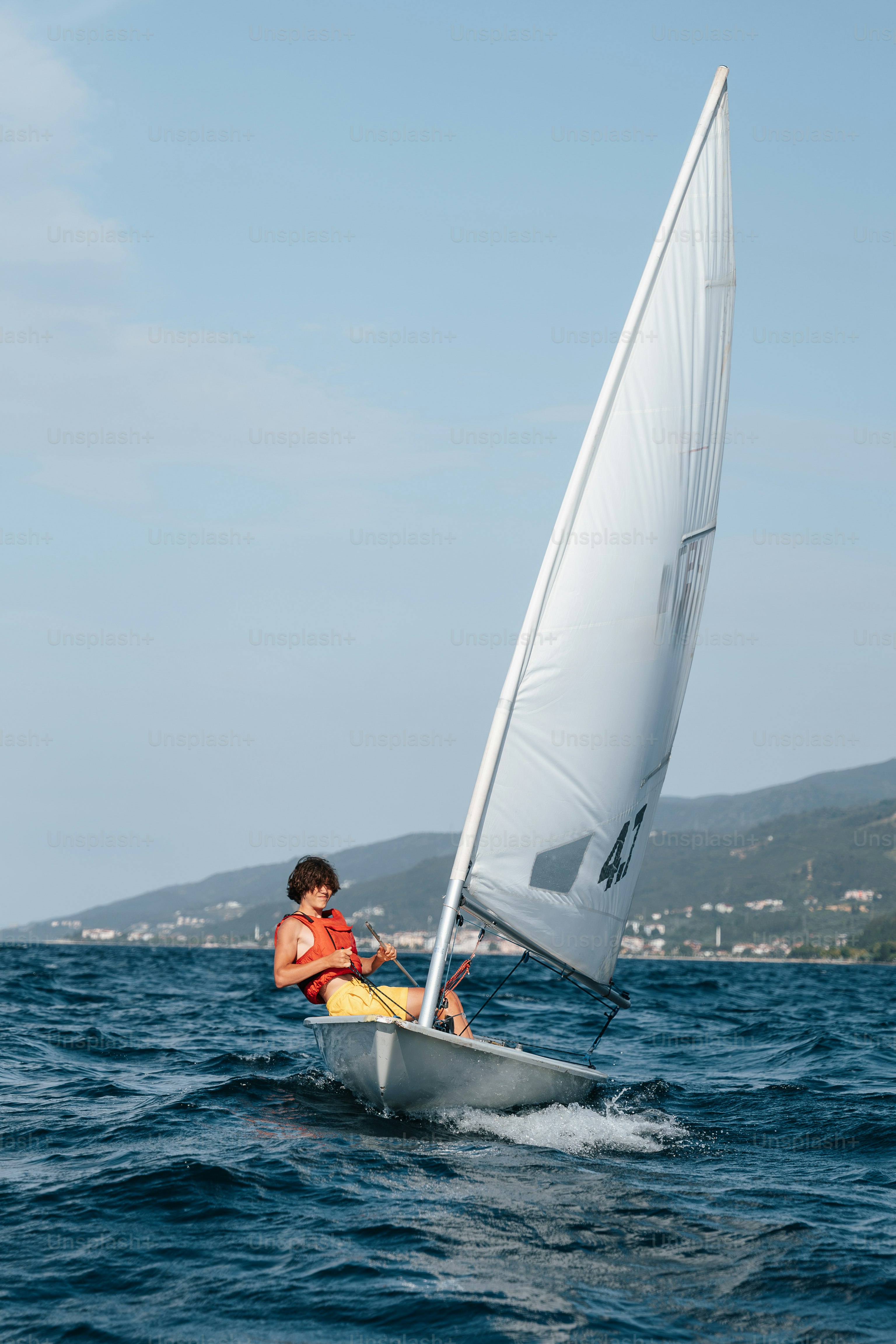Sailor on small sailboat in choppy blue water