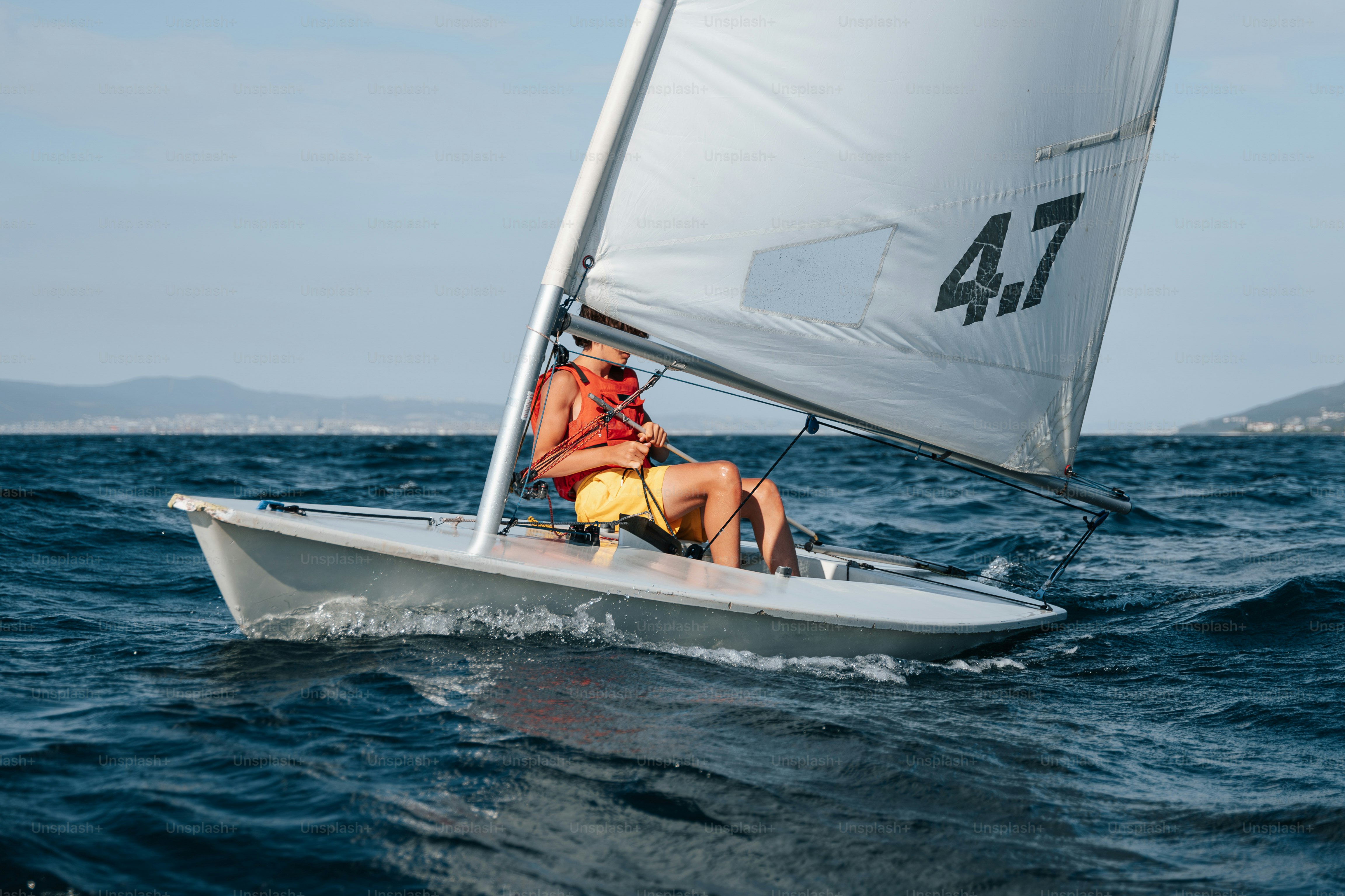 Sailor in life vest on small sailboat