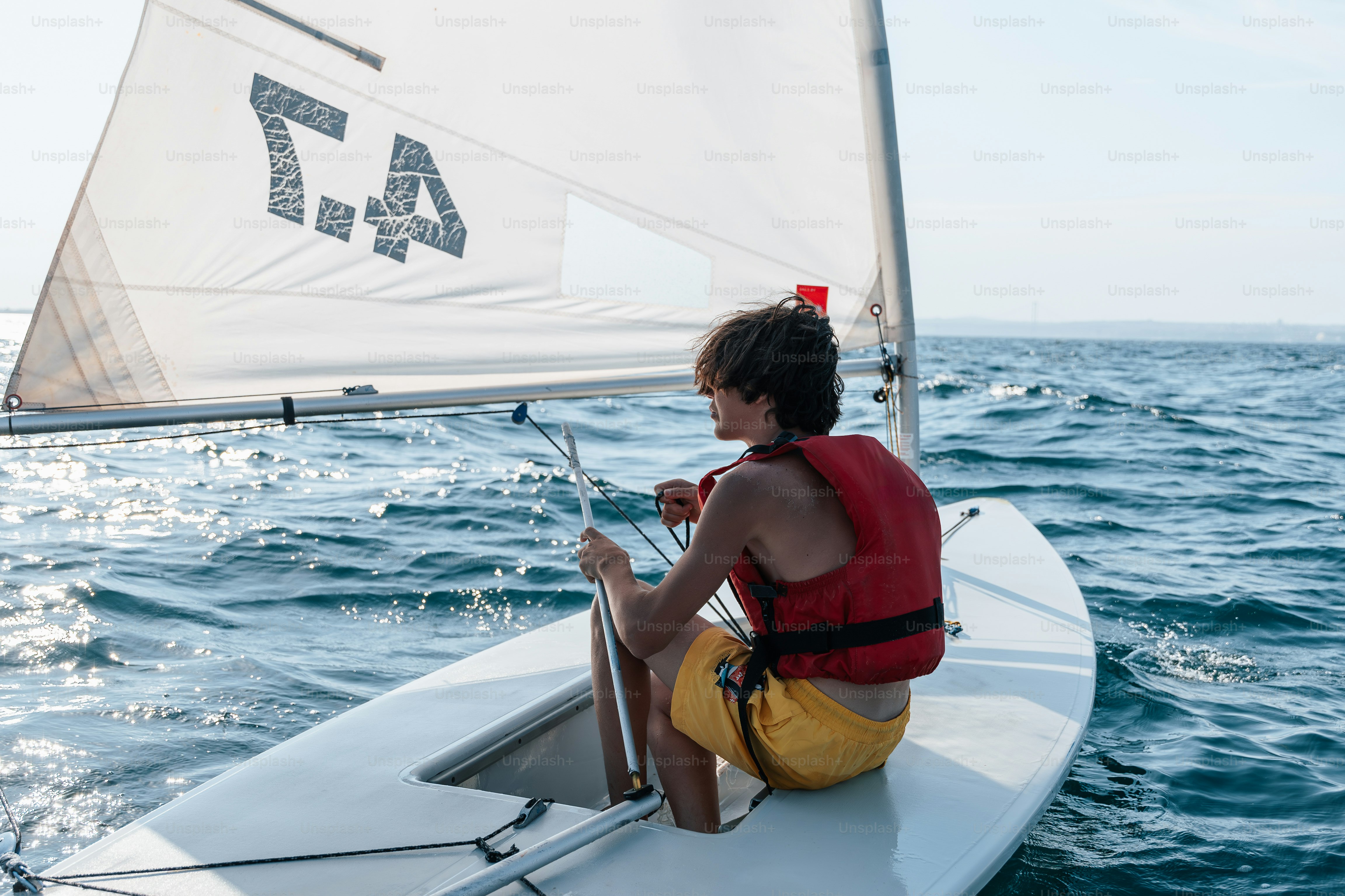 Boy sailing small boat in red life vest