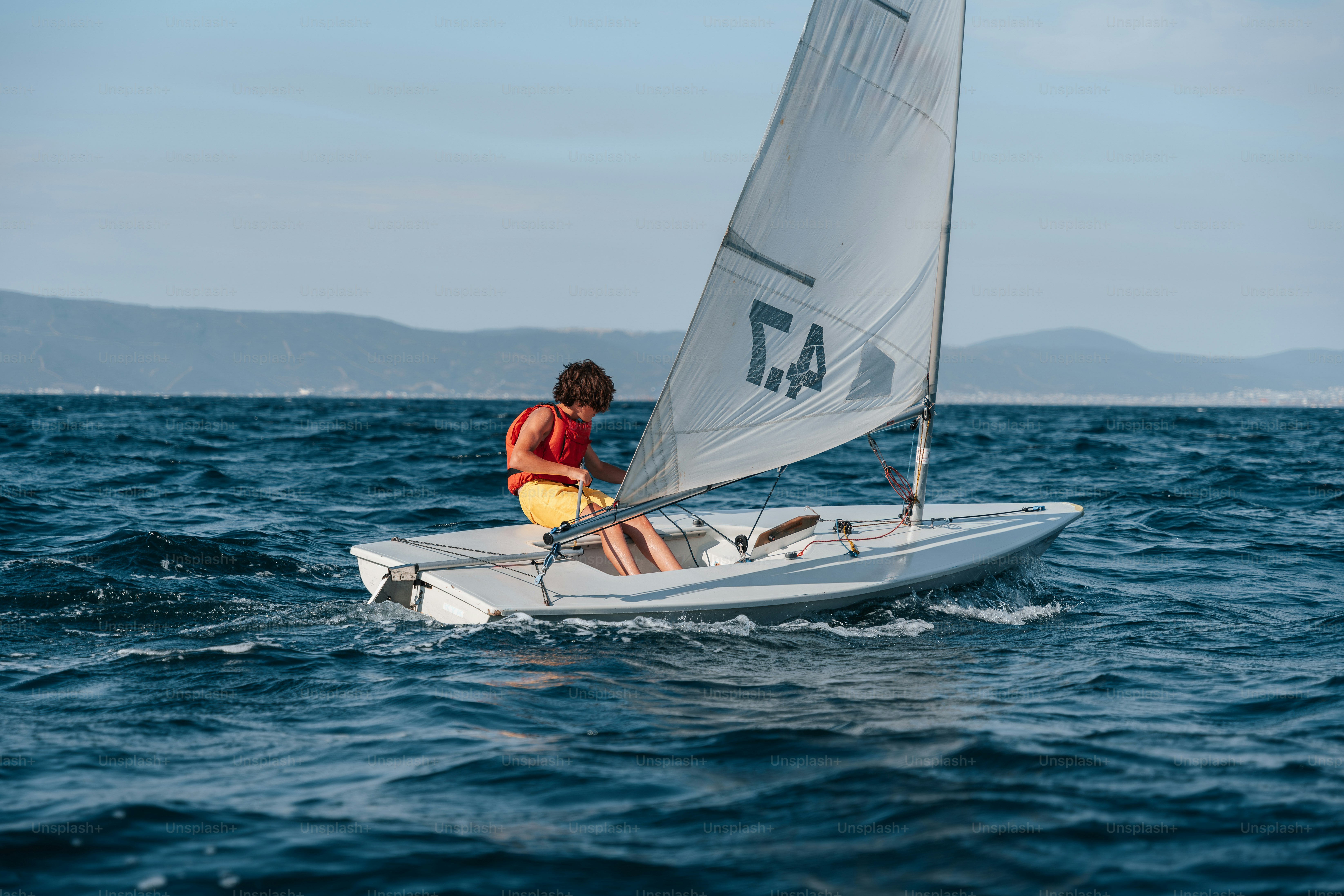 Person sailing small boat on blue ocean