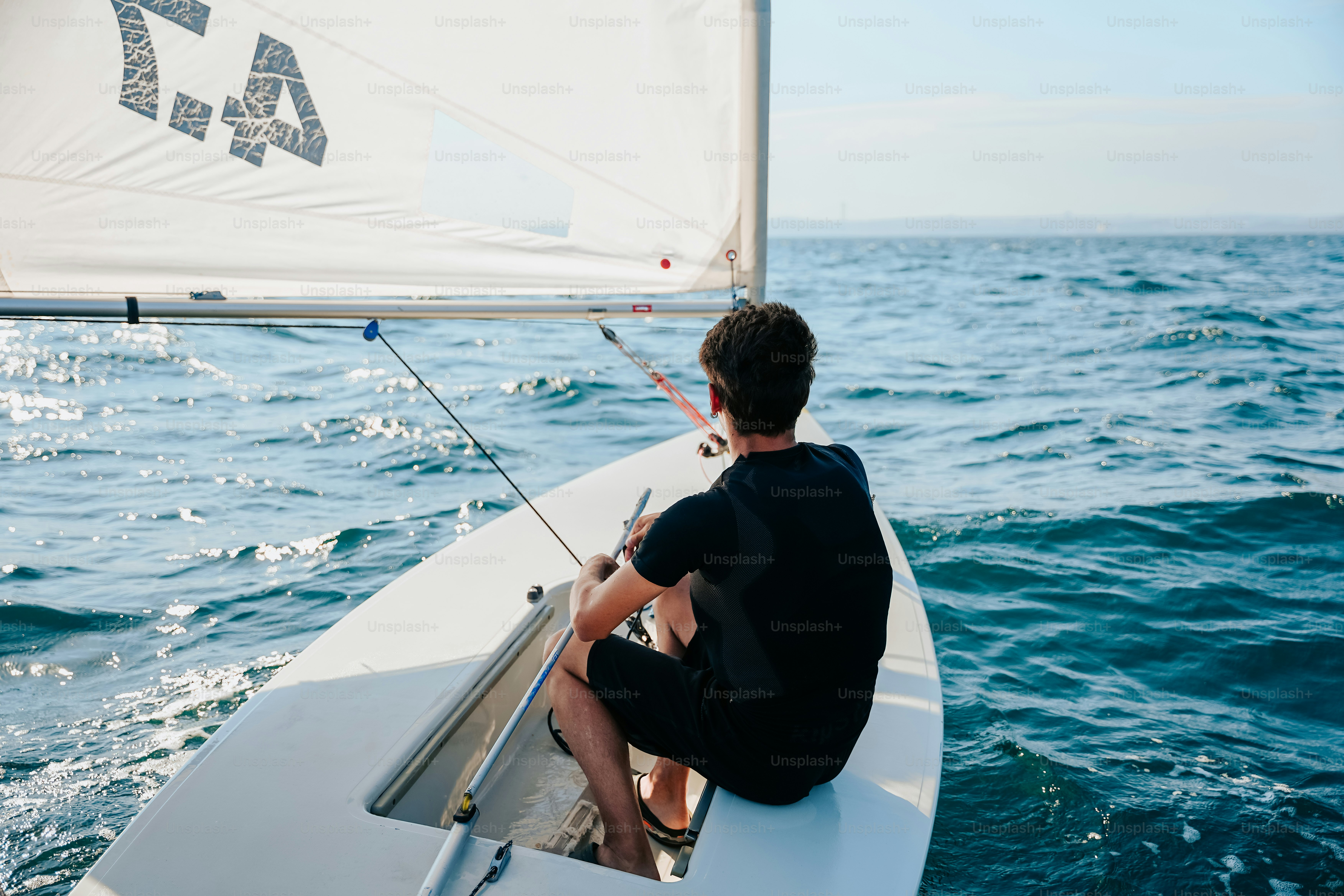 Young man sailing small boat on ocean
