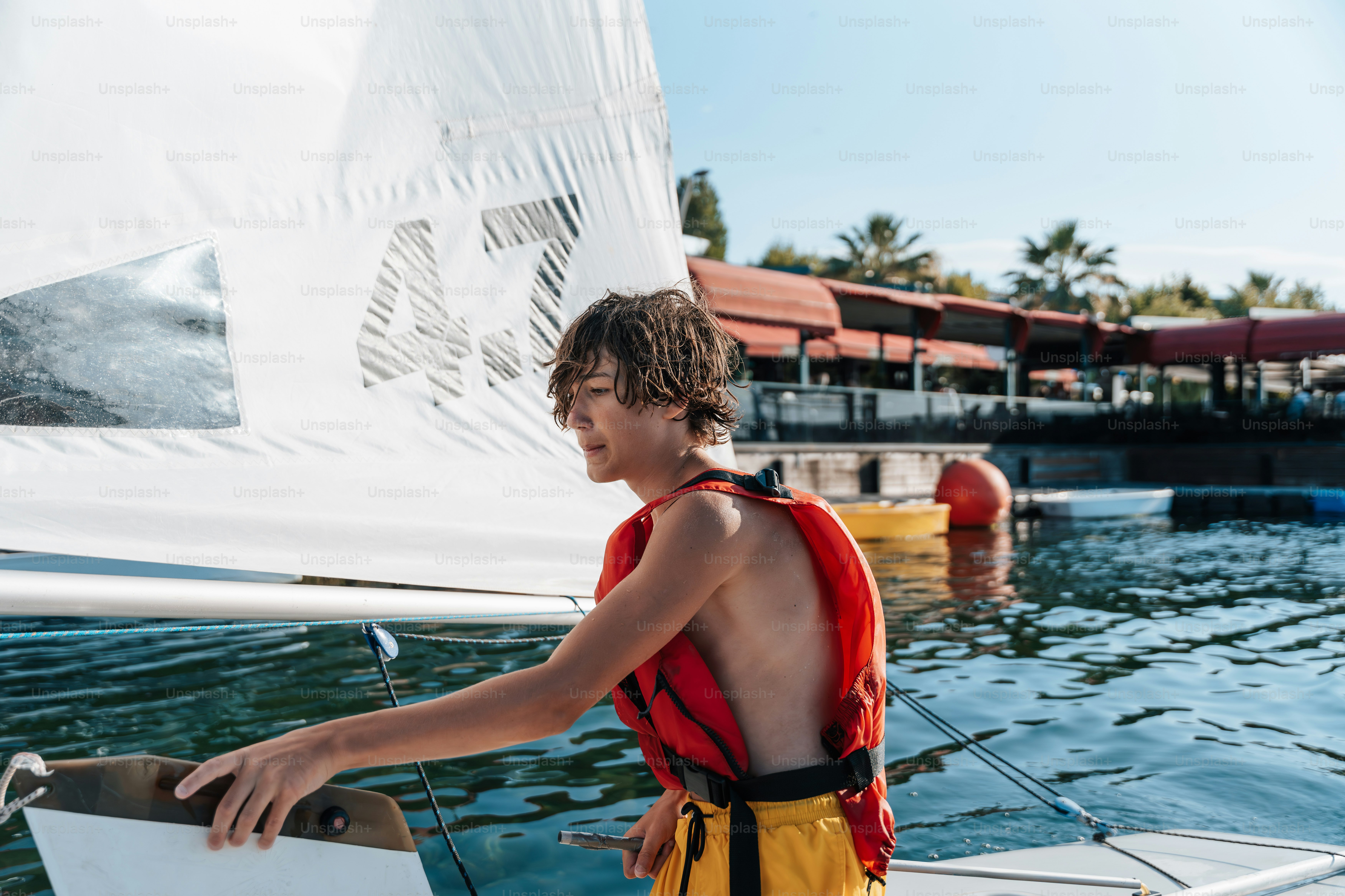 Teenager in life vest on sailboat at resort