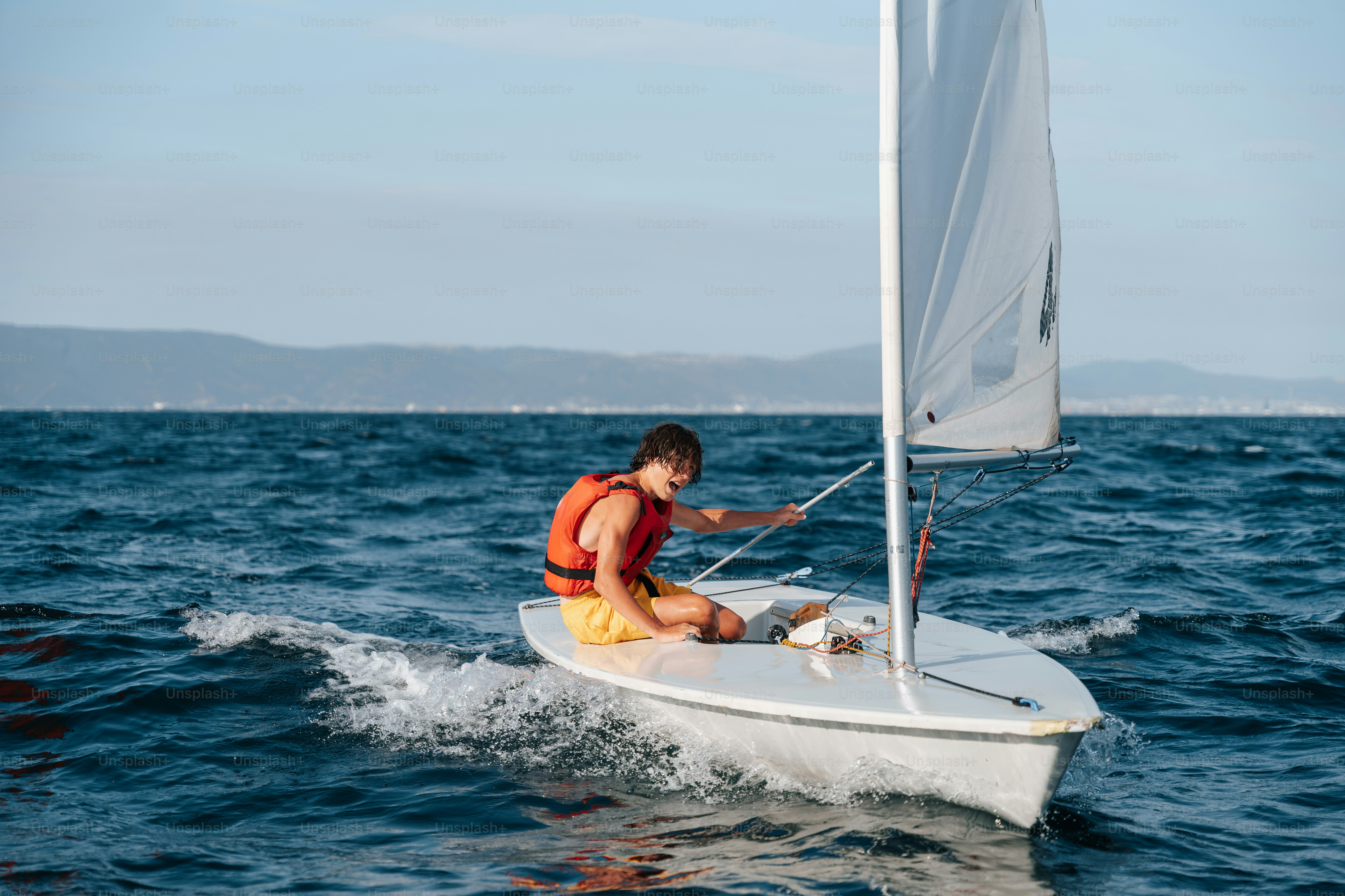 Sailor in life vest on small sailboat