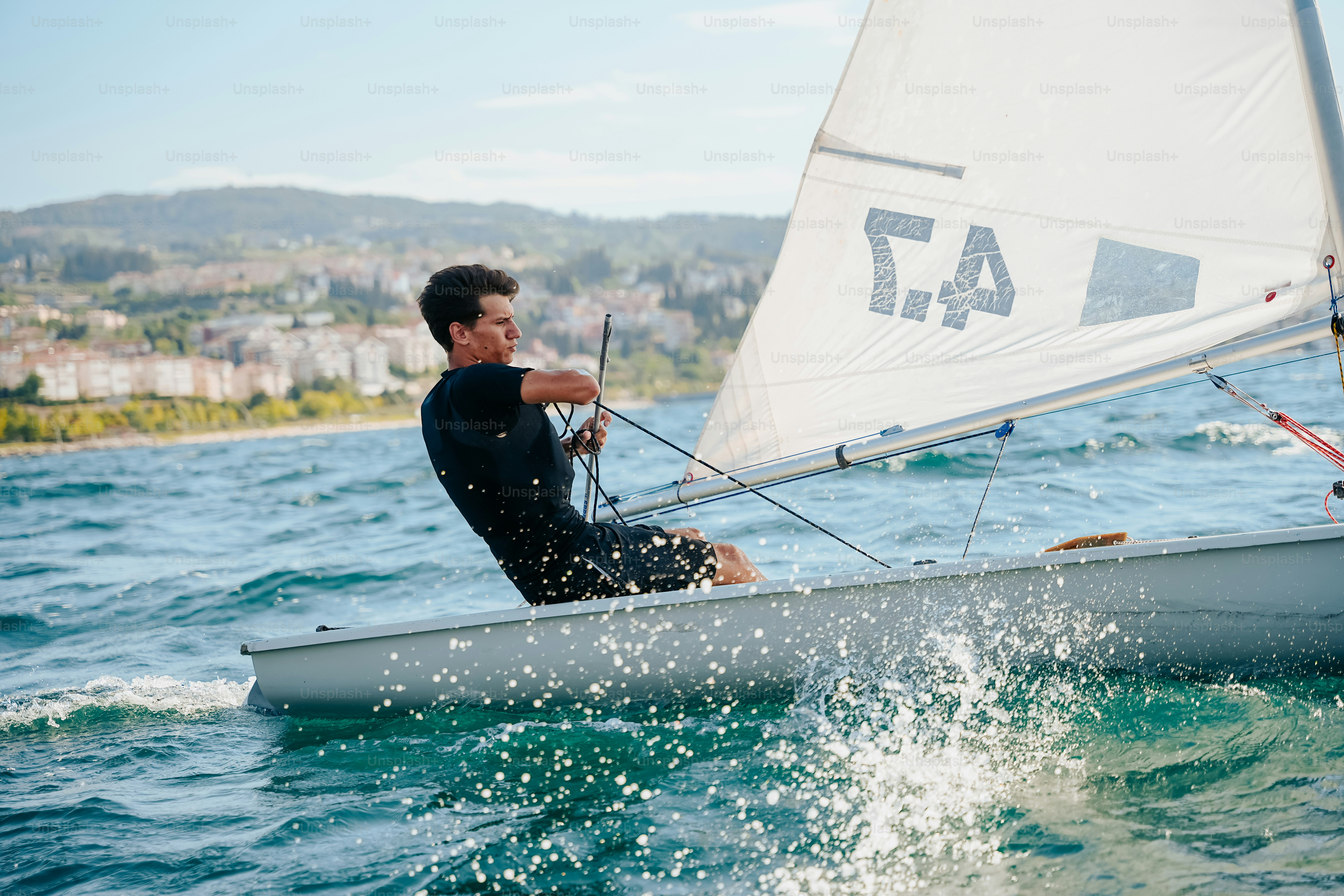 Man sailing small sailboat, splashing through water
