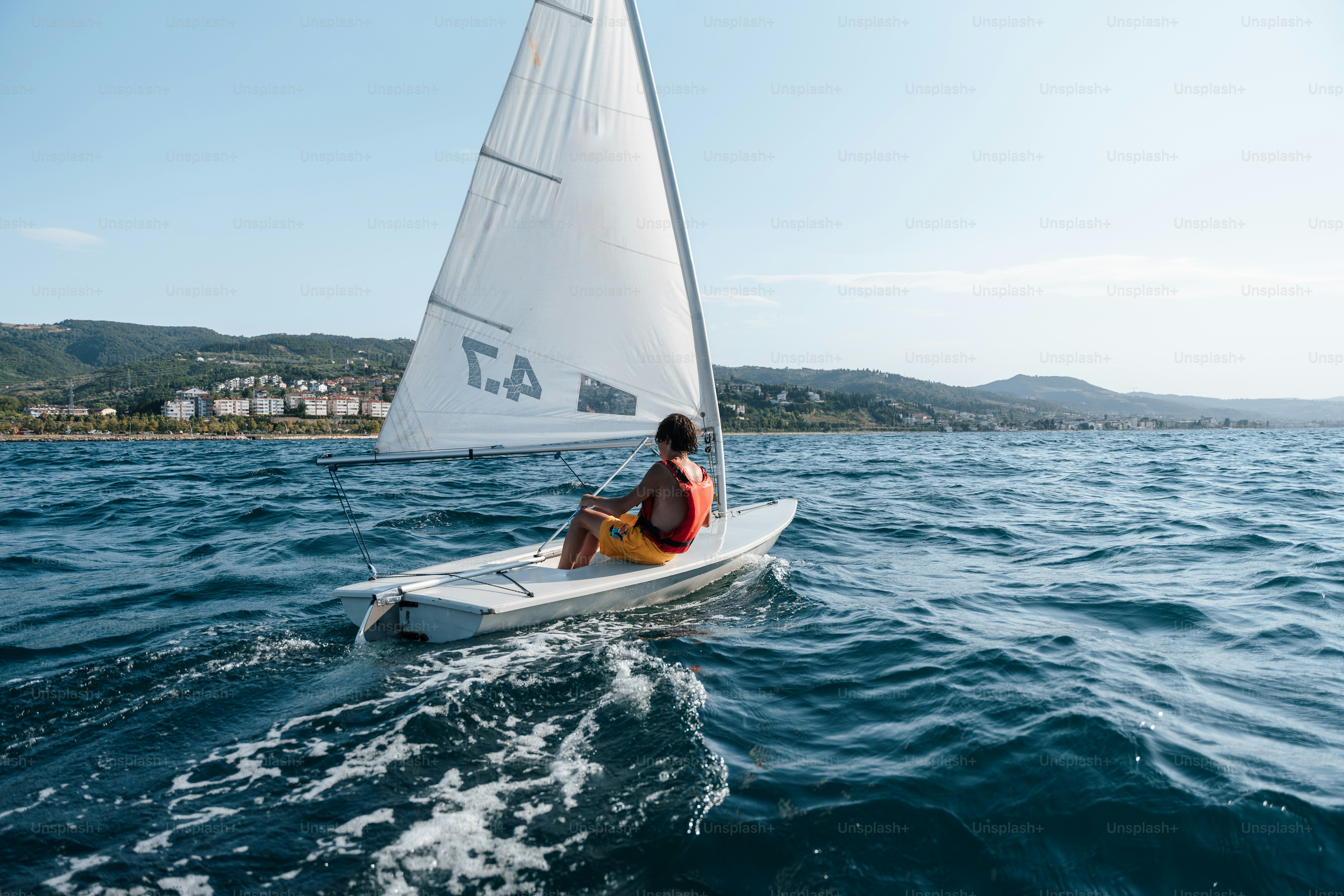 Person sailing a small boat on blue water