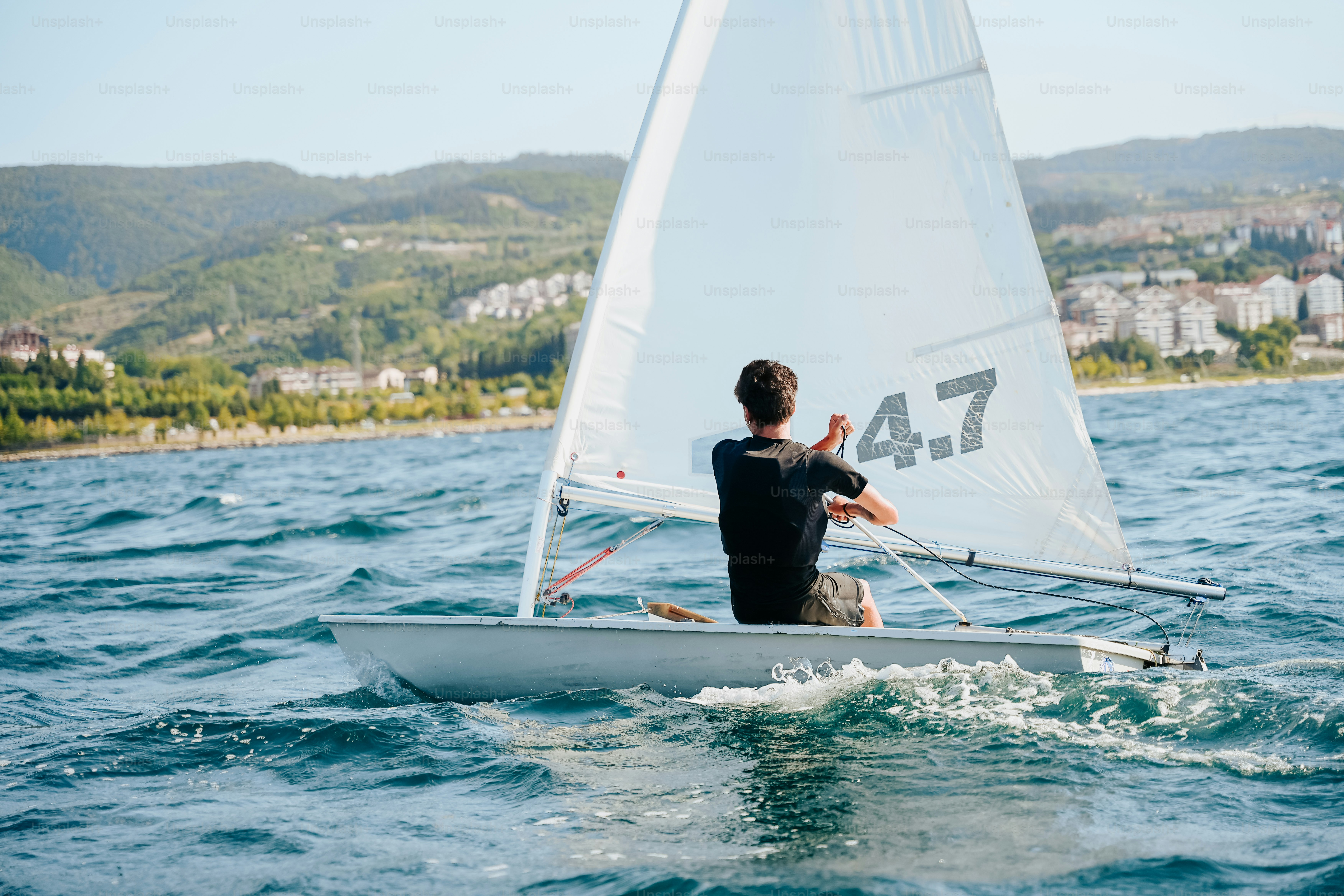 Sailor on small sailboat on wavy blue water