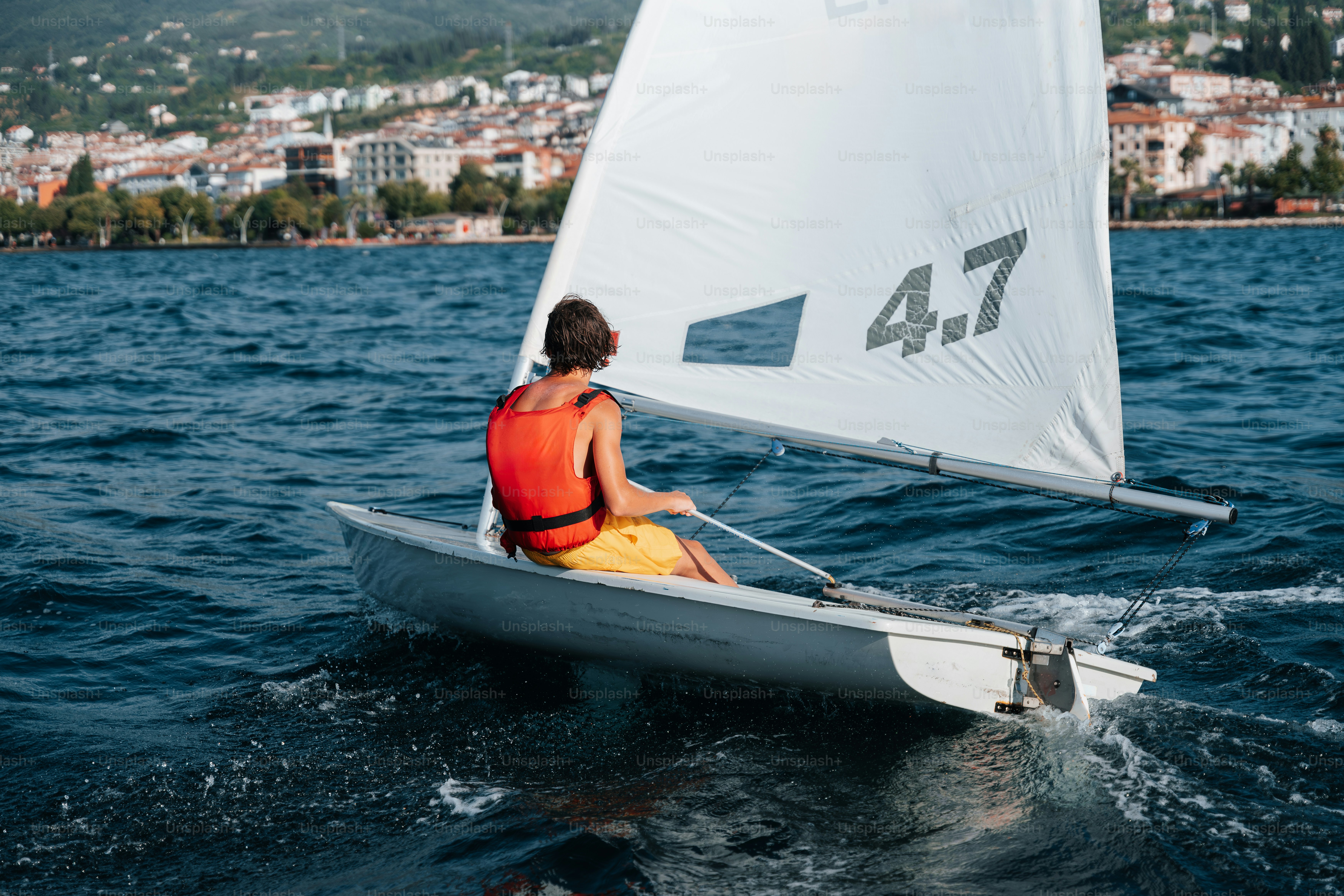 Sailor in life vest on small sailboat
