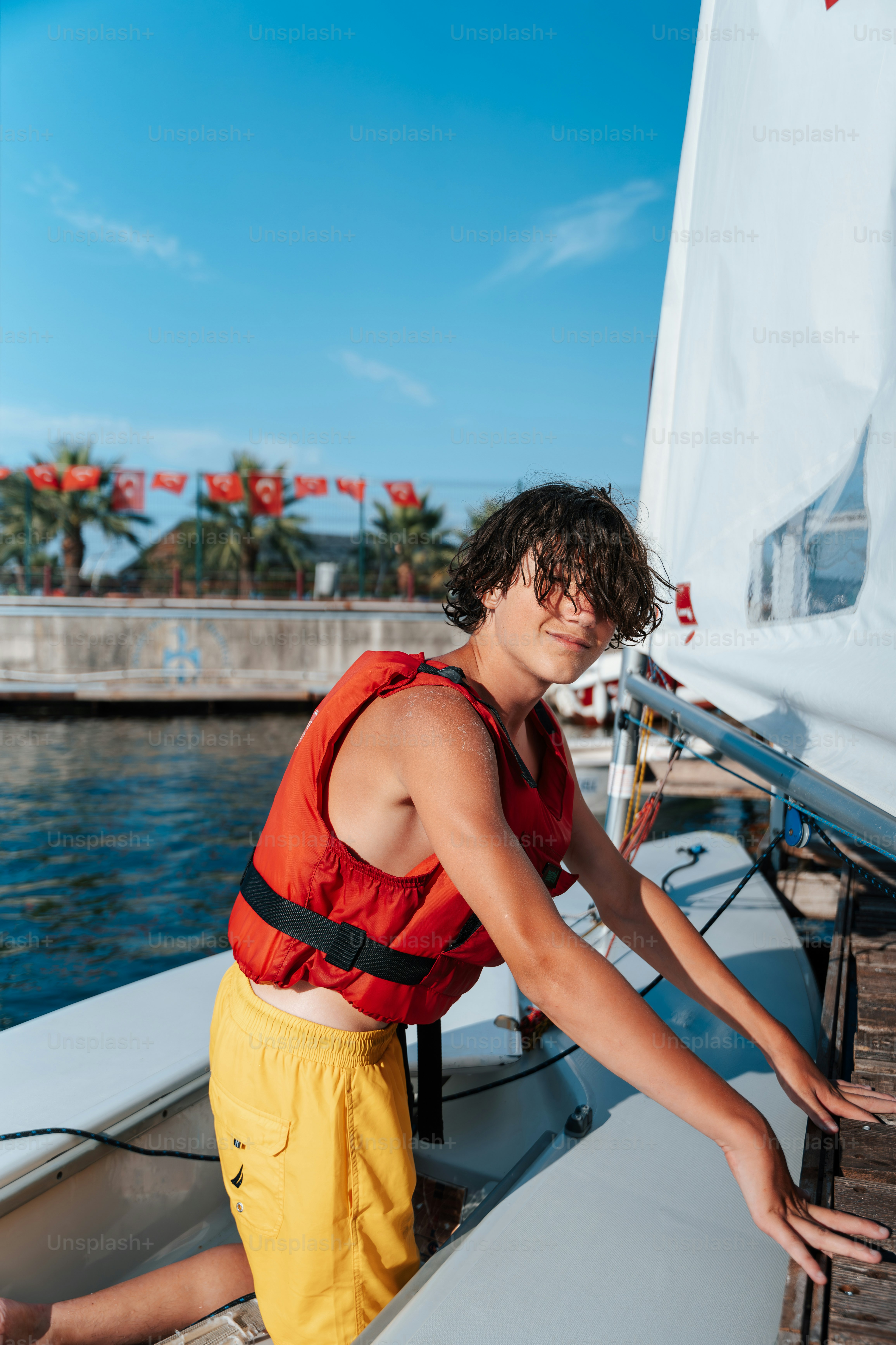 Smiling teenager in red life vest on sailboat