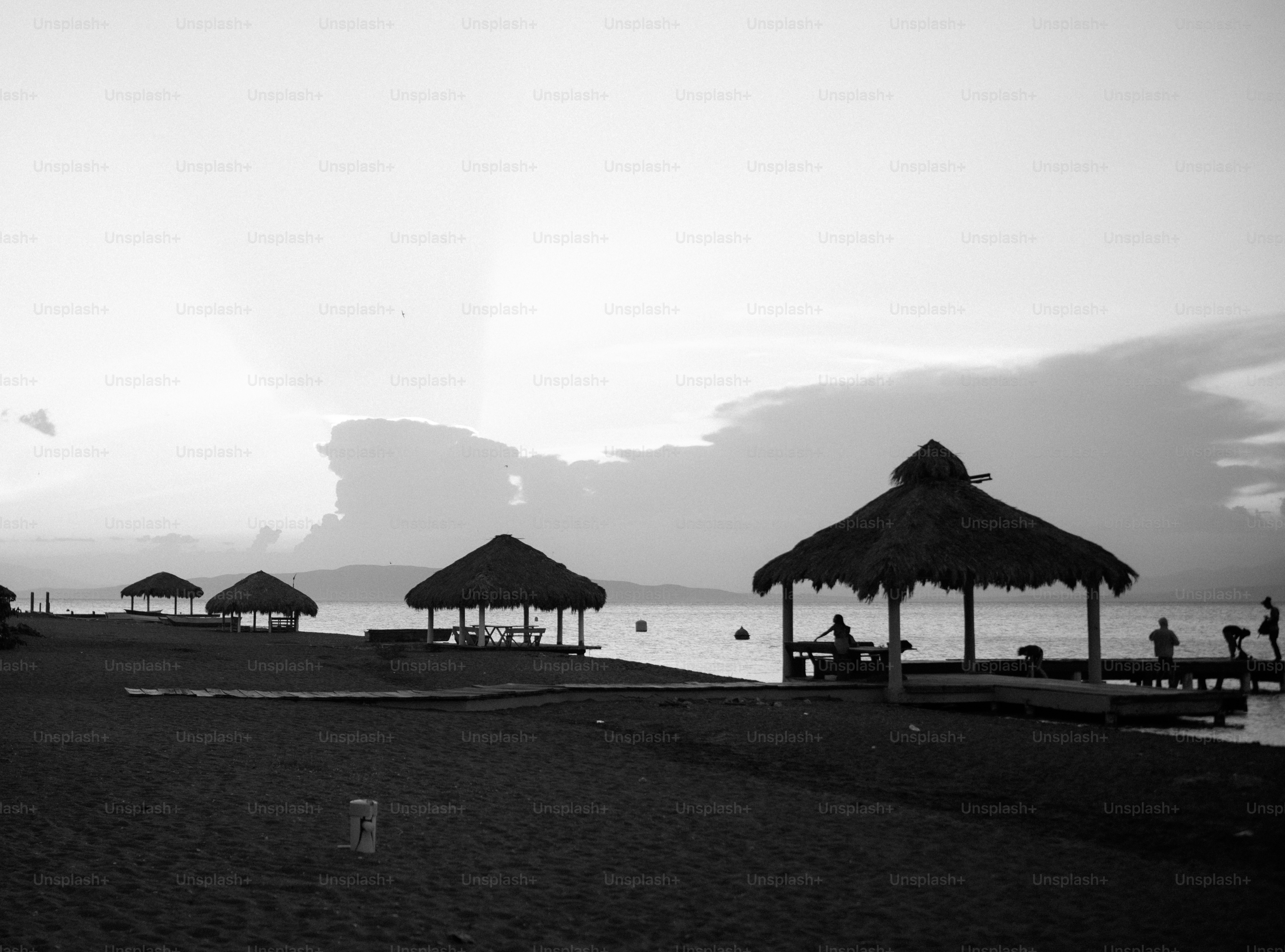 Cabanas e píer de palha na praia preta e branca