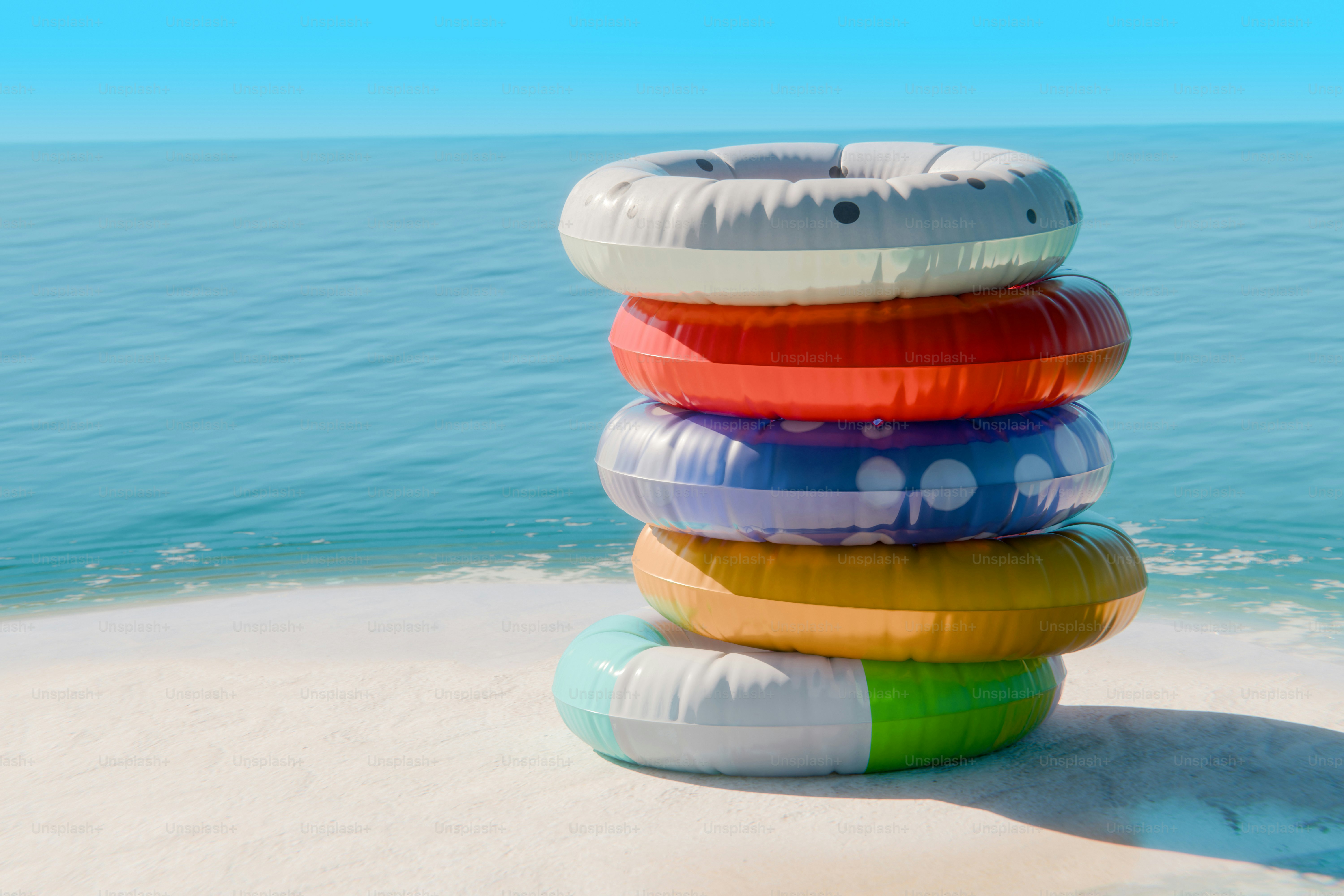 Colorful inflatable rings stacked on sandy beach