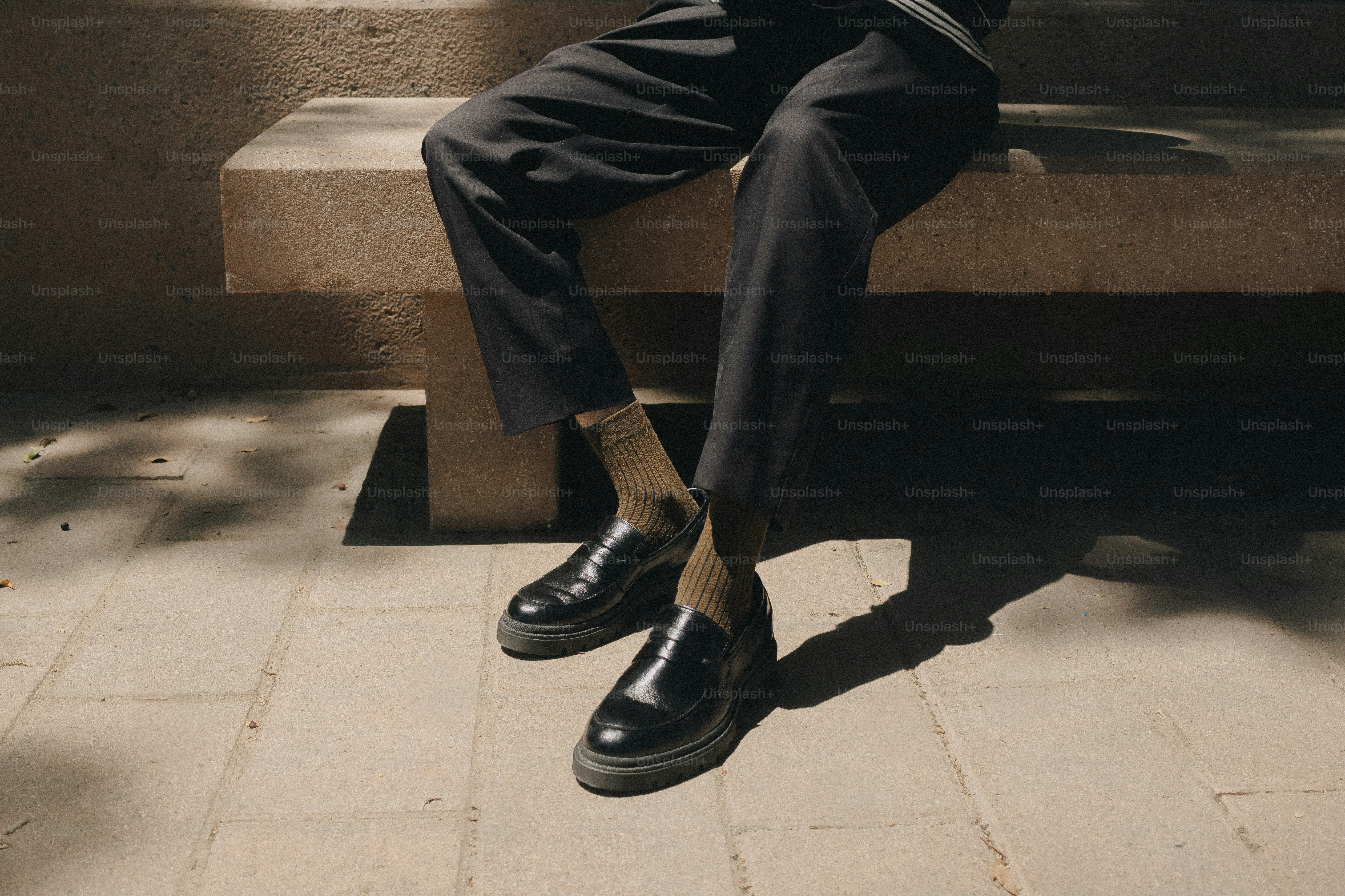 Pernas de pessoa em mocassins pretos no banco de pedra
