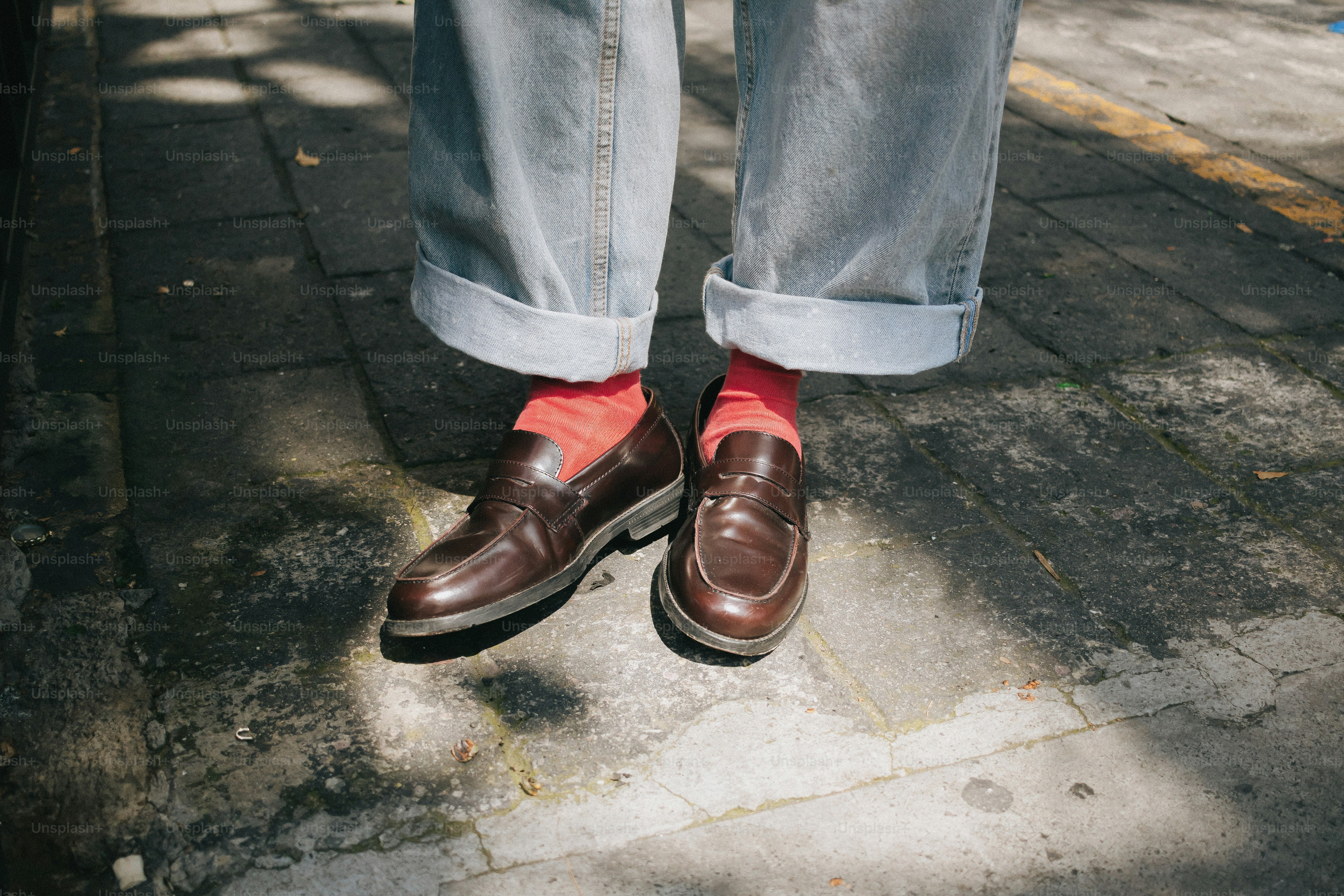 Brown loafers with red socks and cuffed jeans
