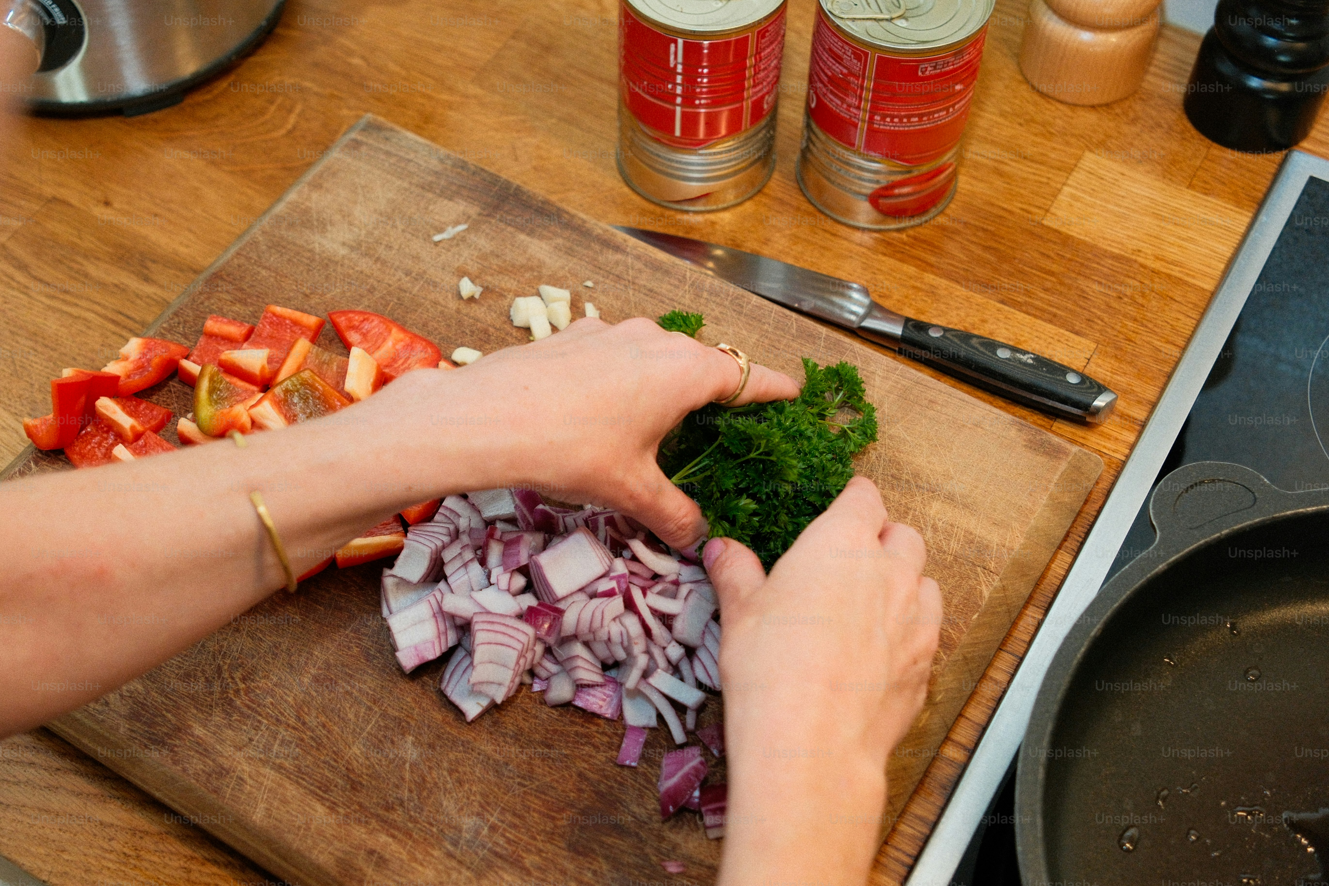 Hands chopping red onion, bell pepper, and parsley
