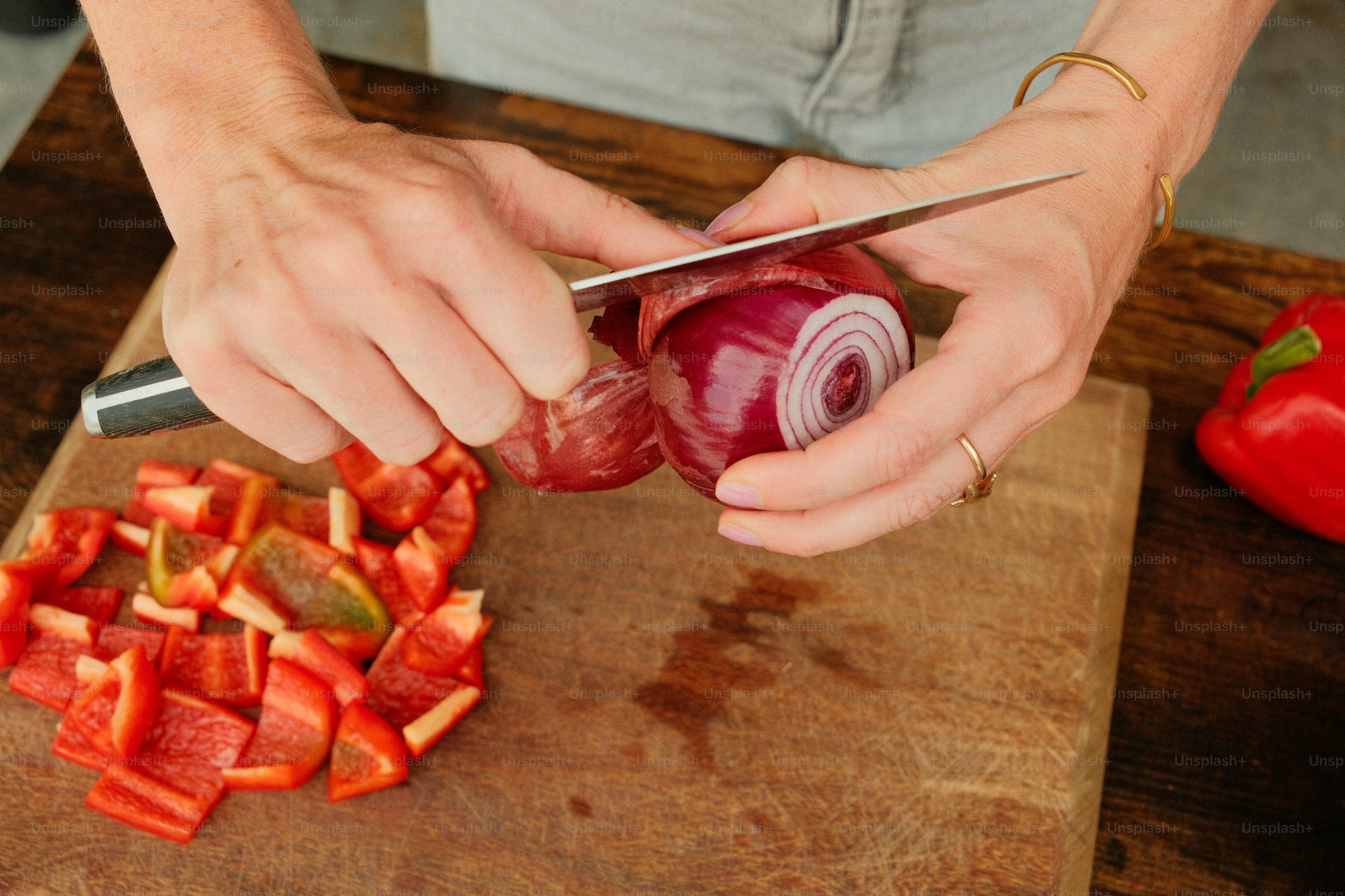Dicing red onion and bell pepper on wooden board