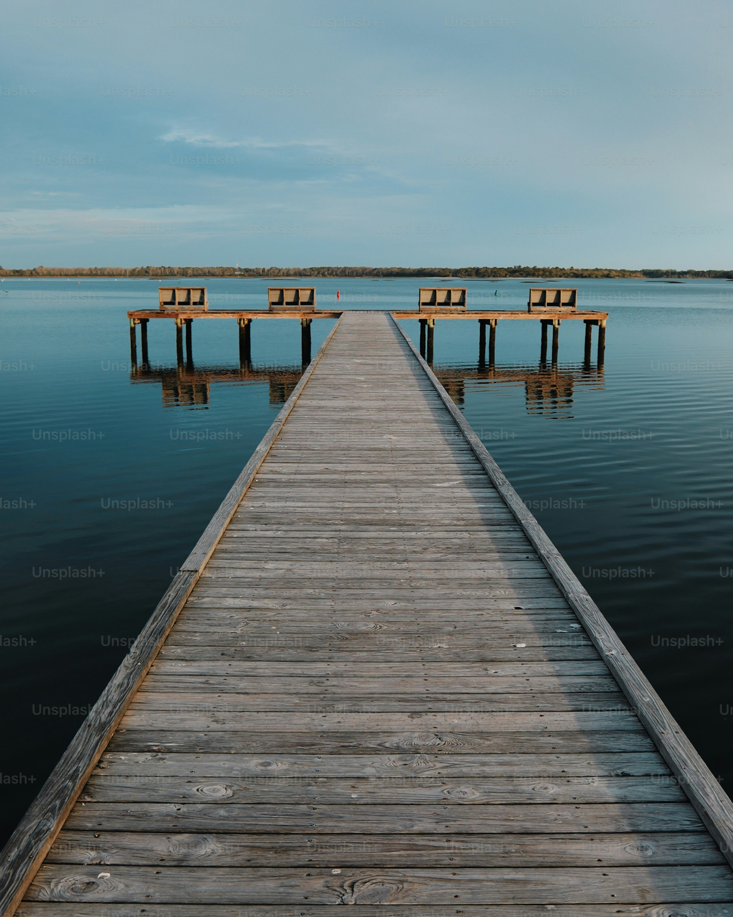Weathered wooden dock extends into calm water with benches
