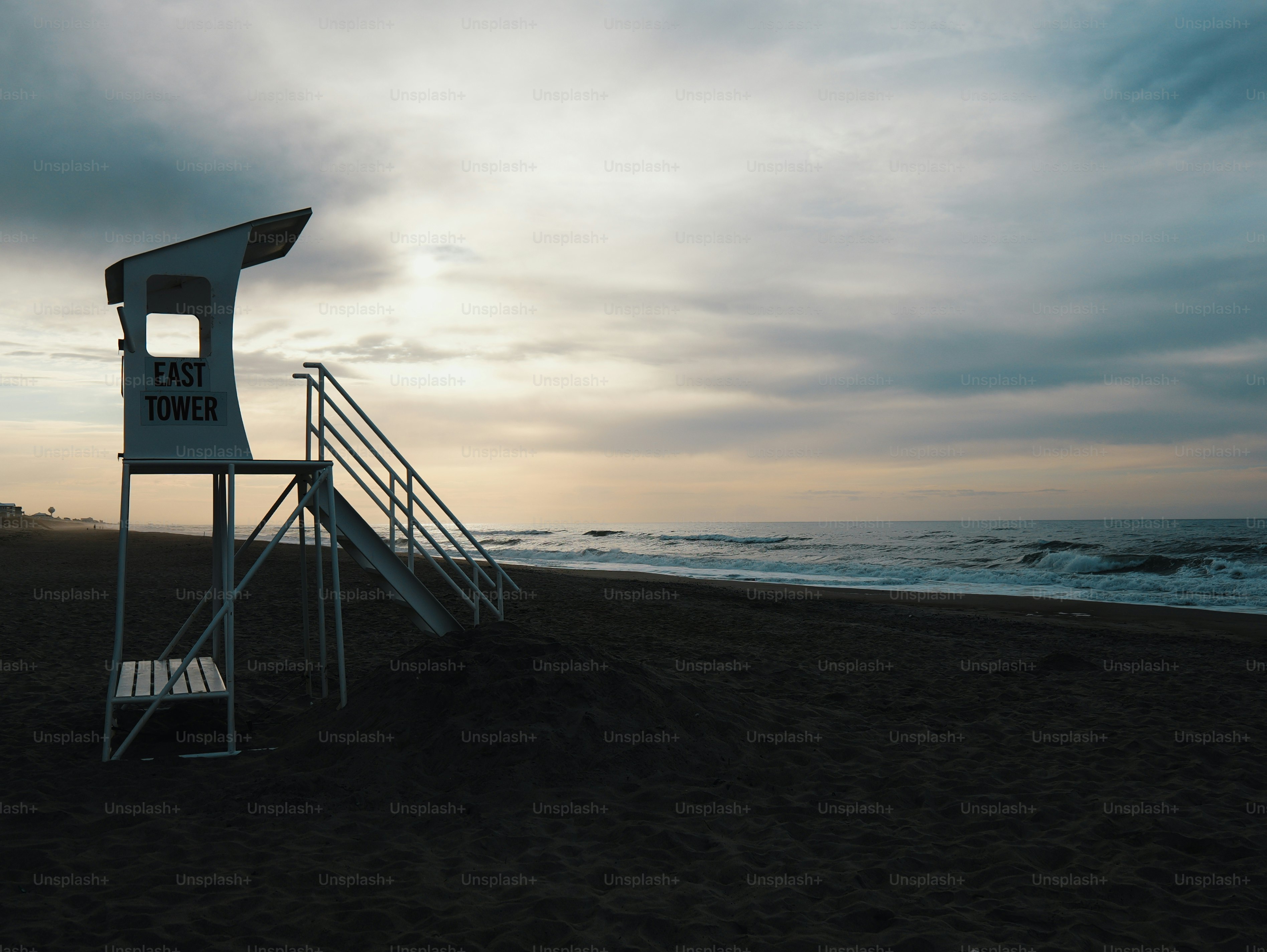 Lifeguard tower on beach under dramatic evening sky