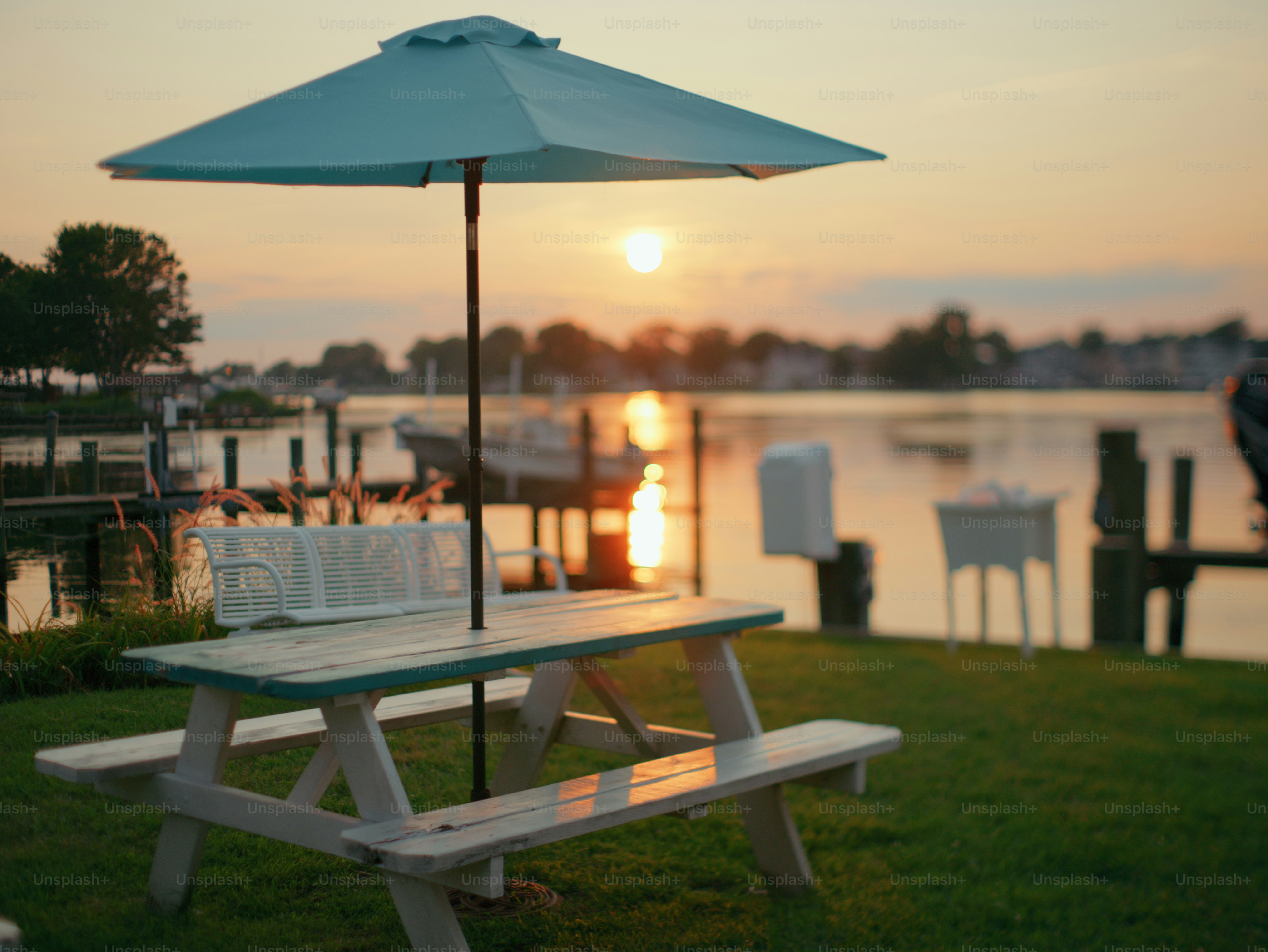Waterfront picnic table with umbrella at sunset