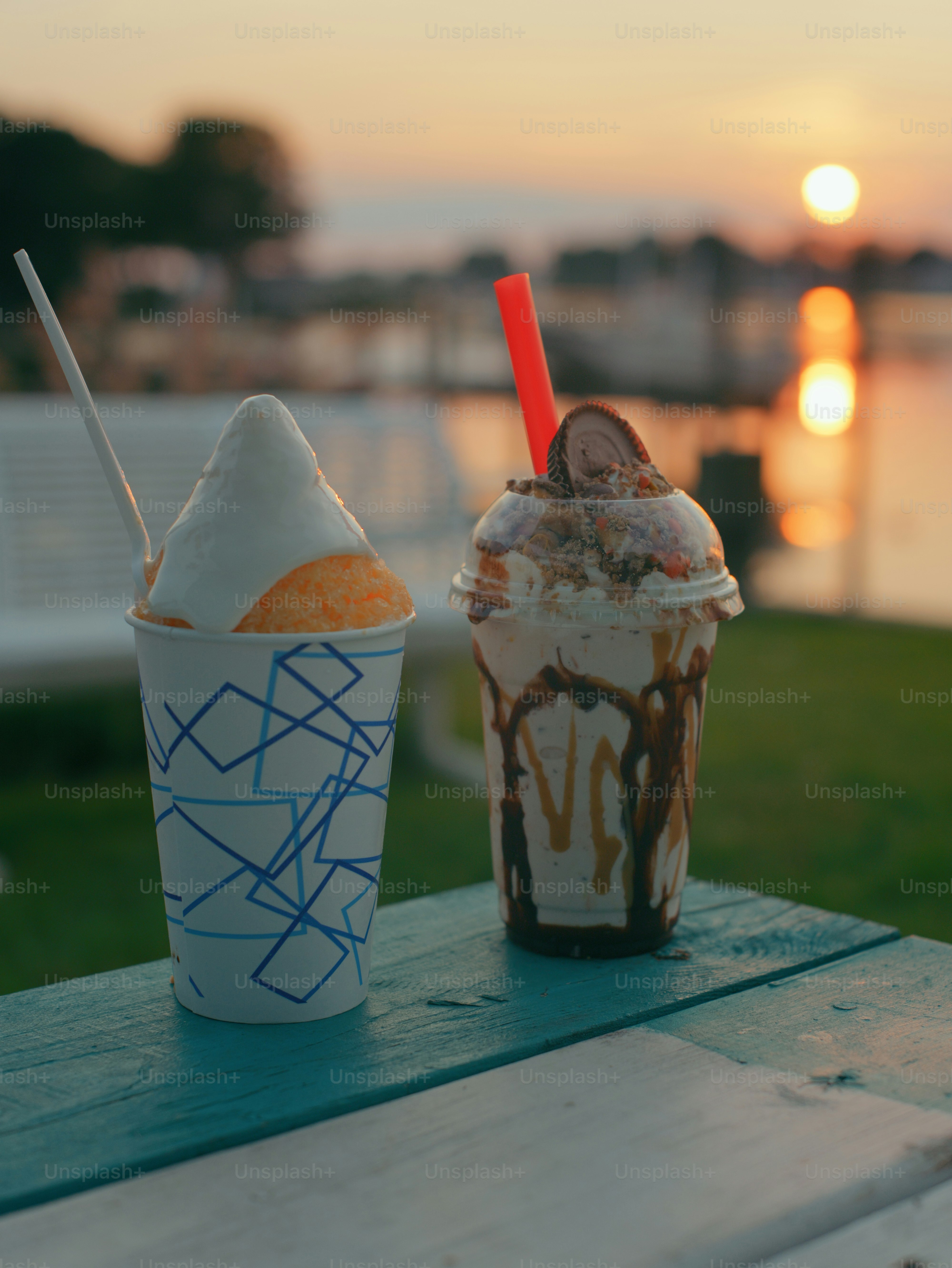 Milkshake and snow cone on table at sunset