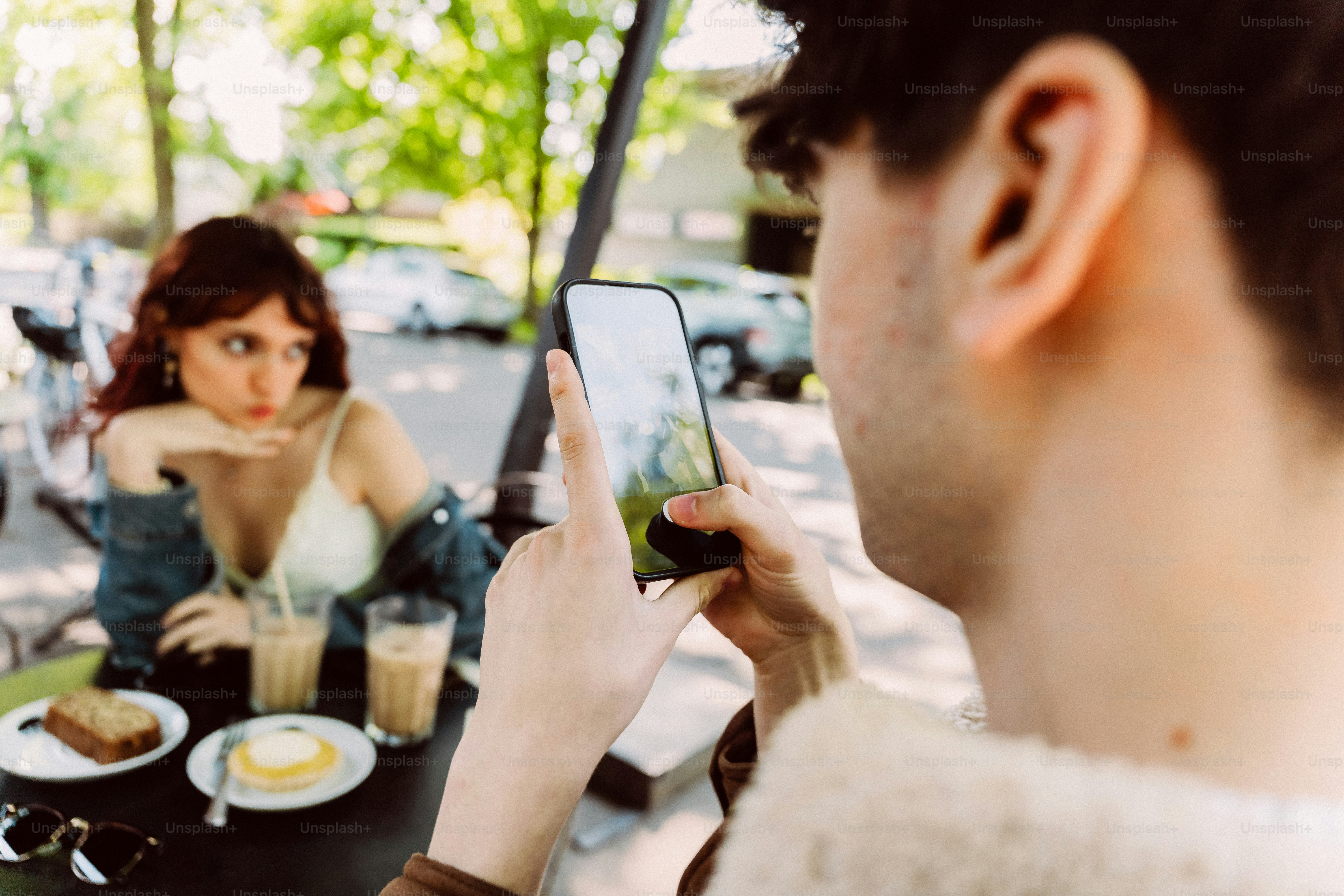 Man photographing woman at cafe table