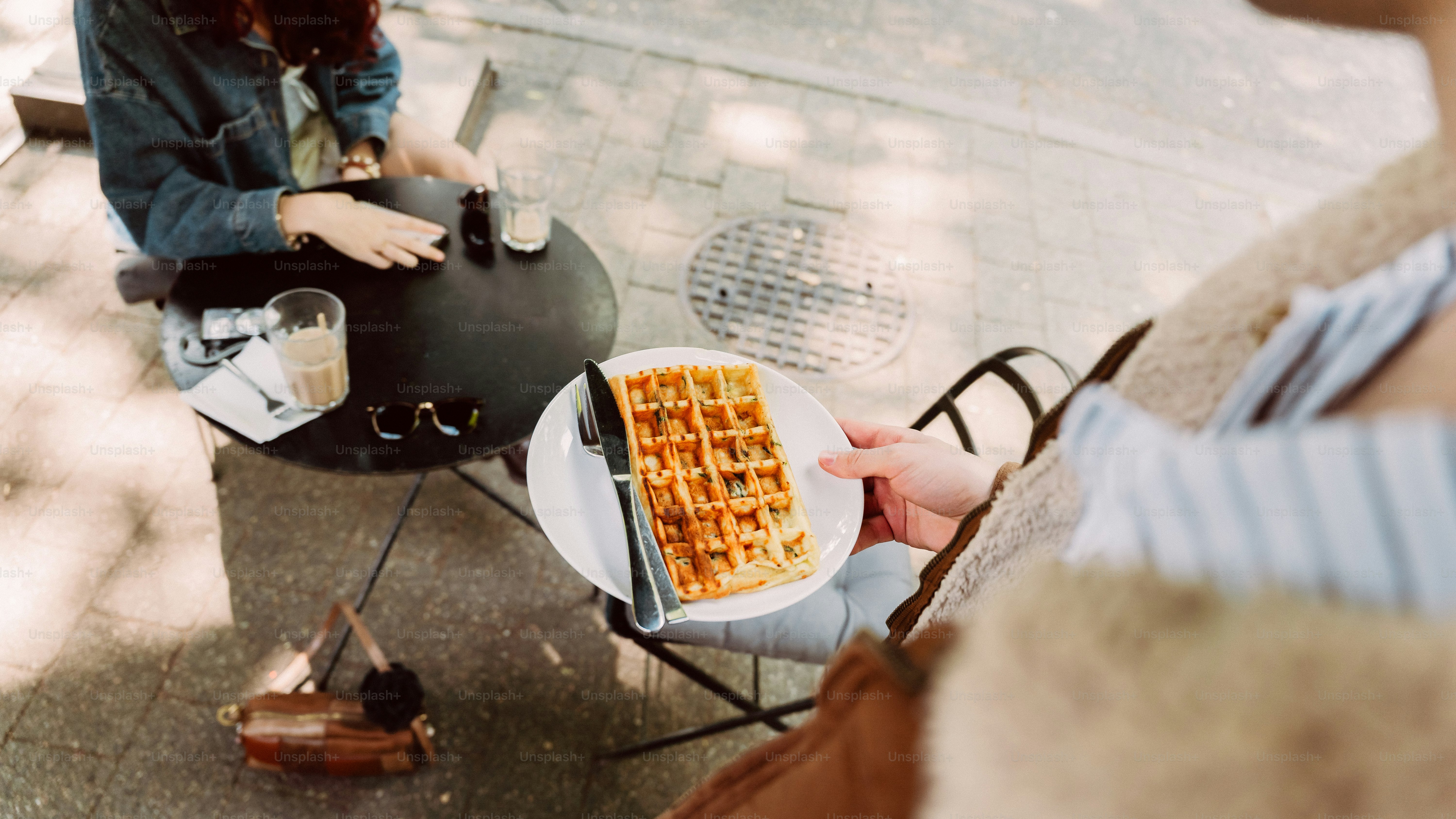 Person holding a waffle at an outdoor cafe