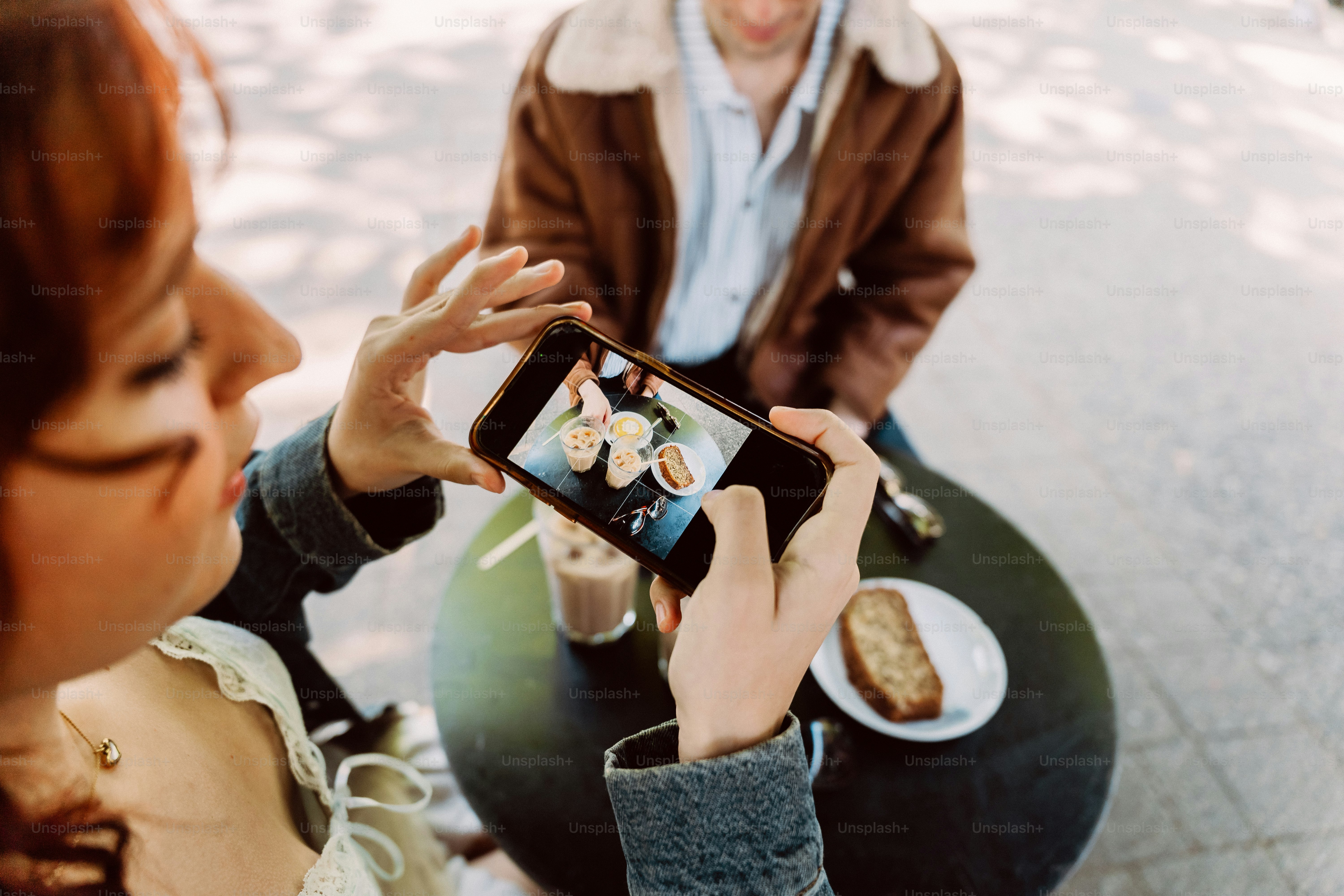 Woman capturing dessert and coffee with smartphone