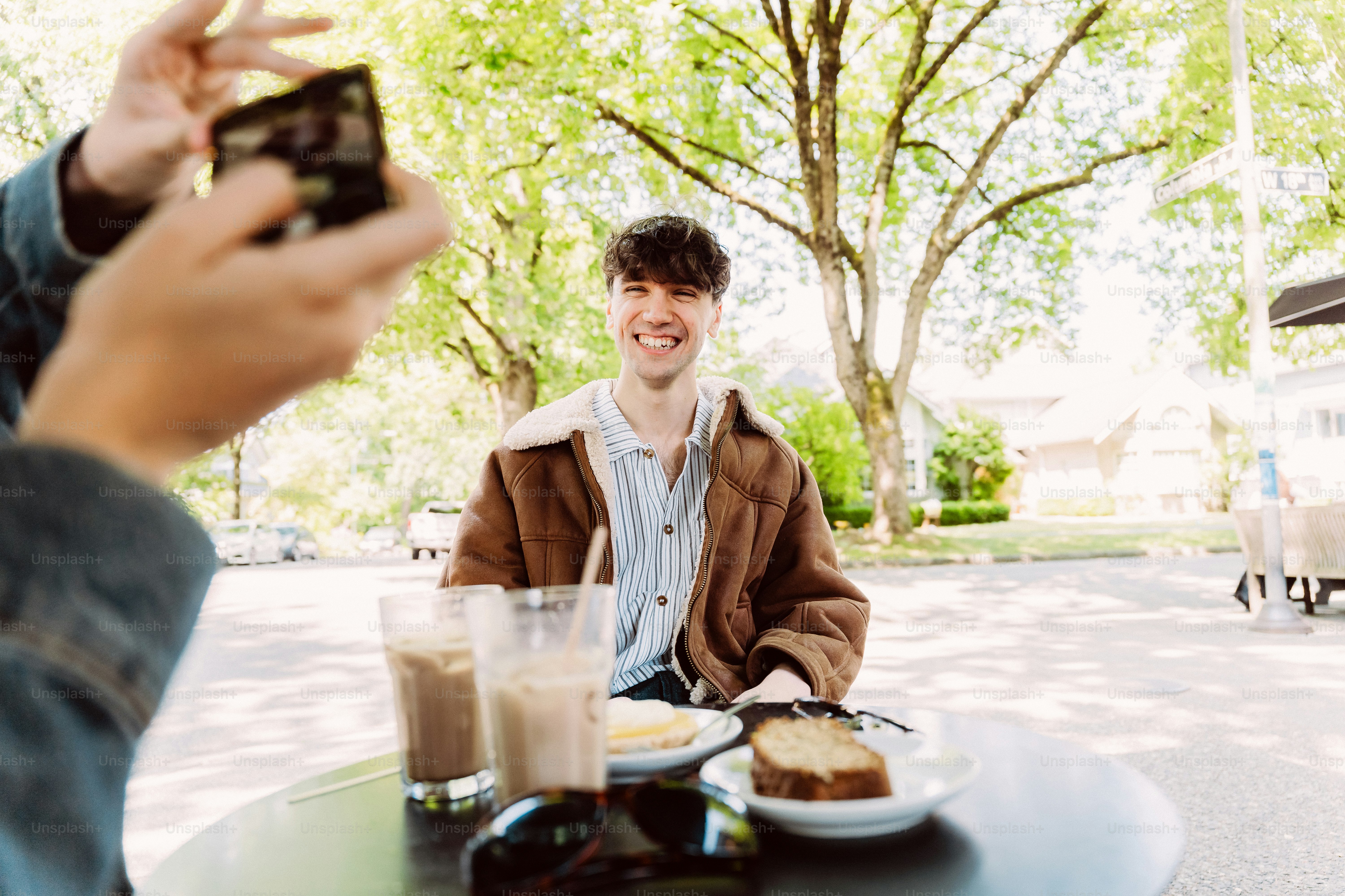Smiling man at outdoor cafe captured by phone