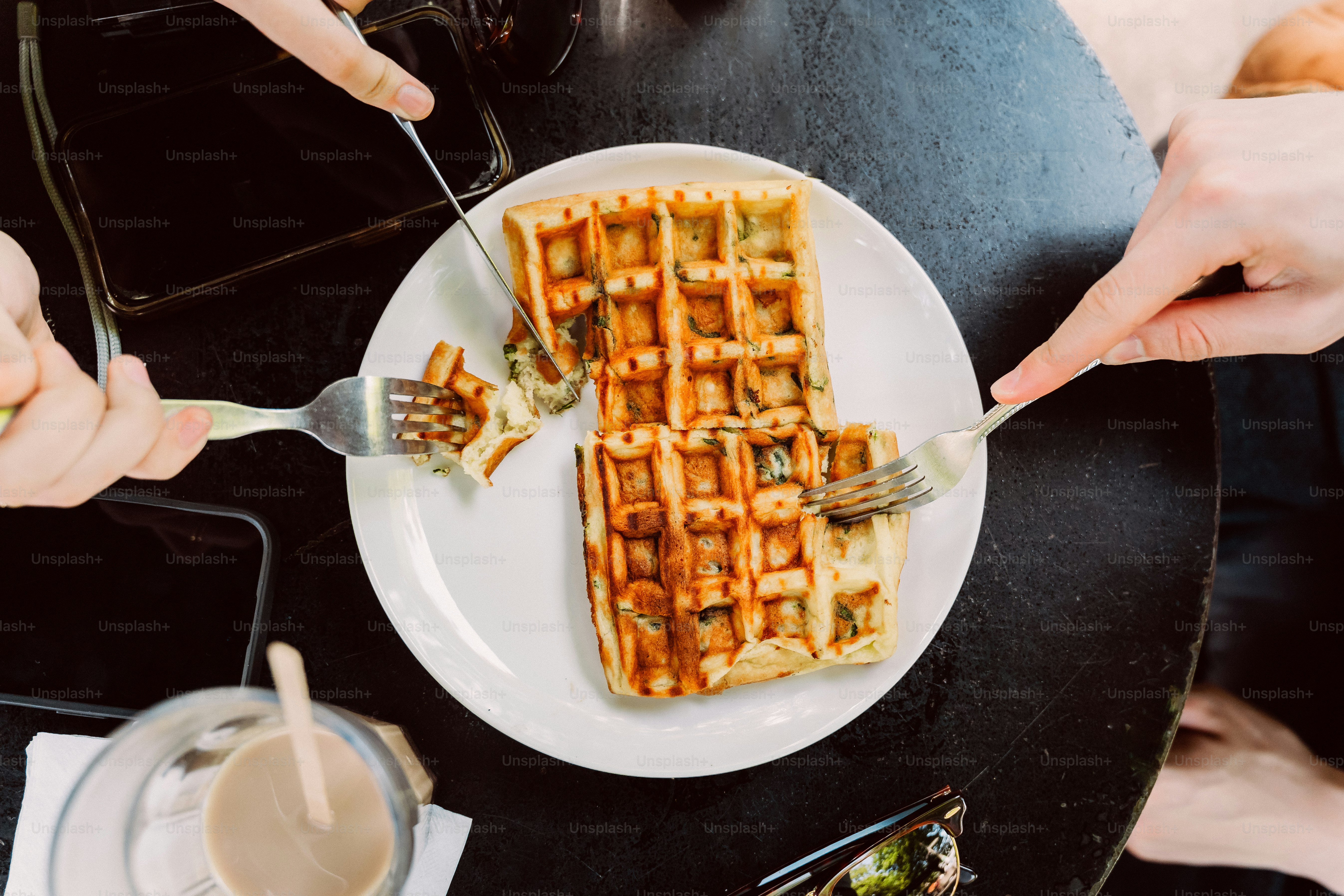 Hands cutting waffles on a white plate