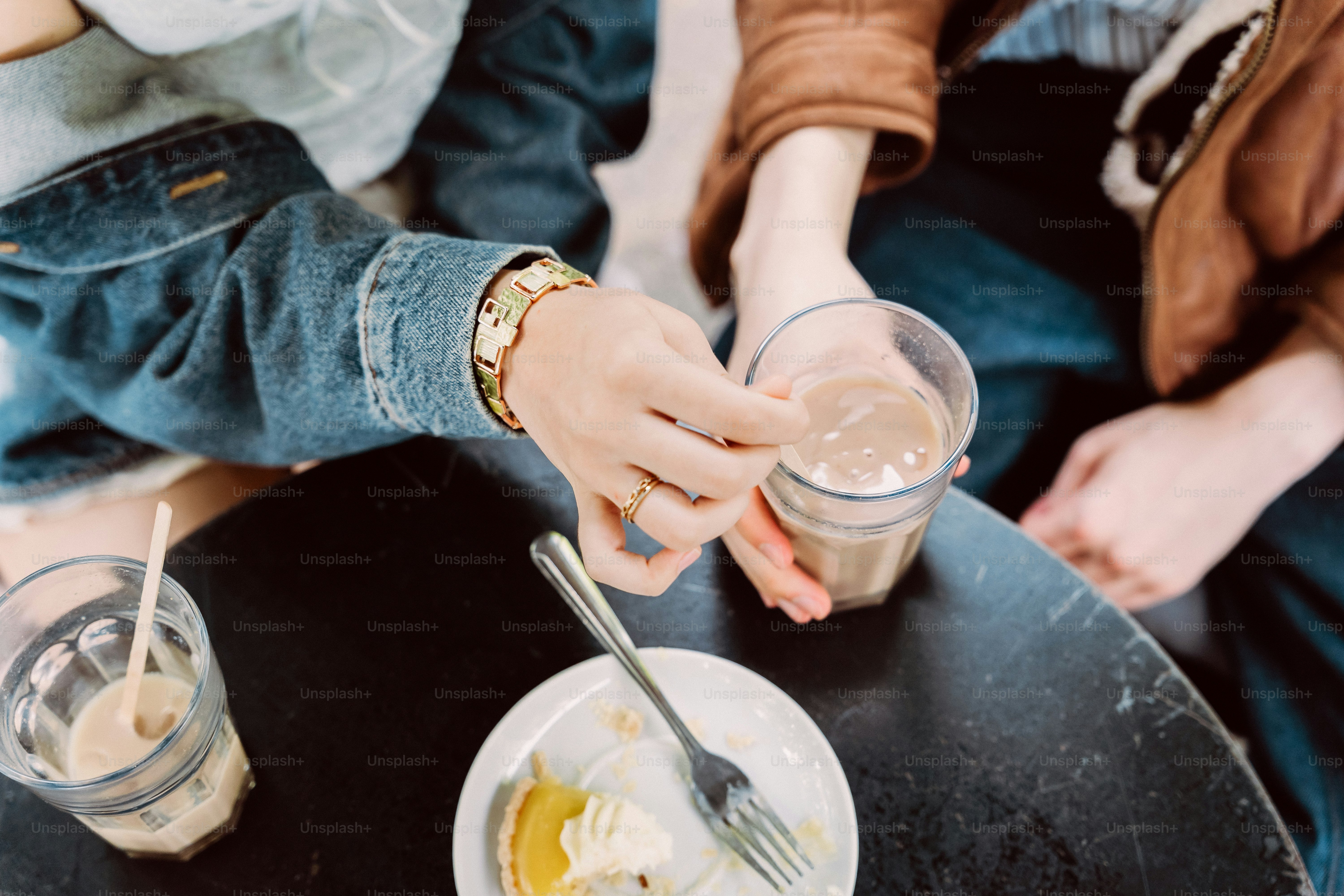 Hands stirring drinks and eating dessert at a table