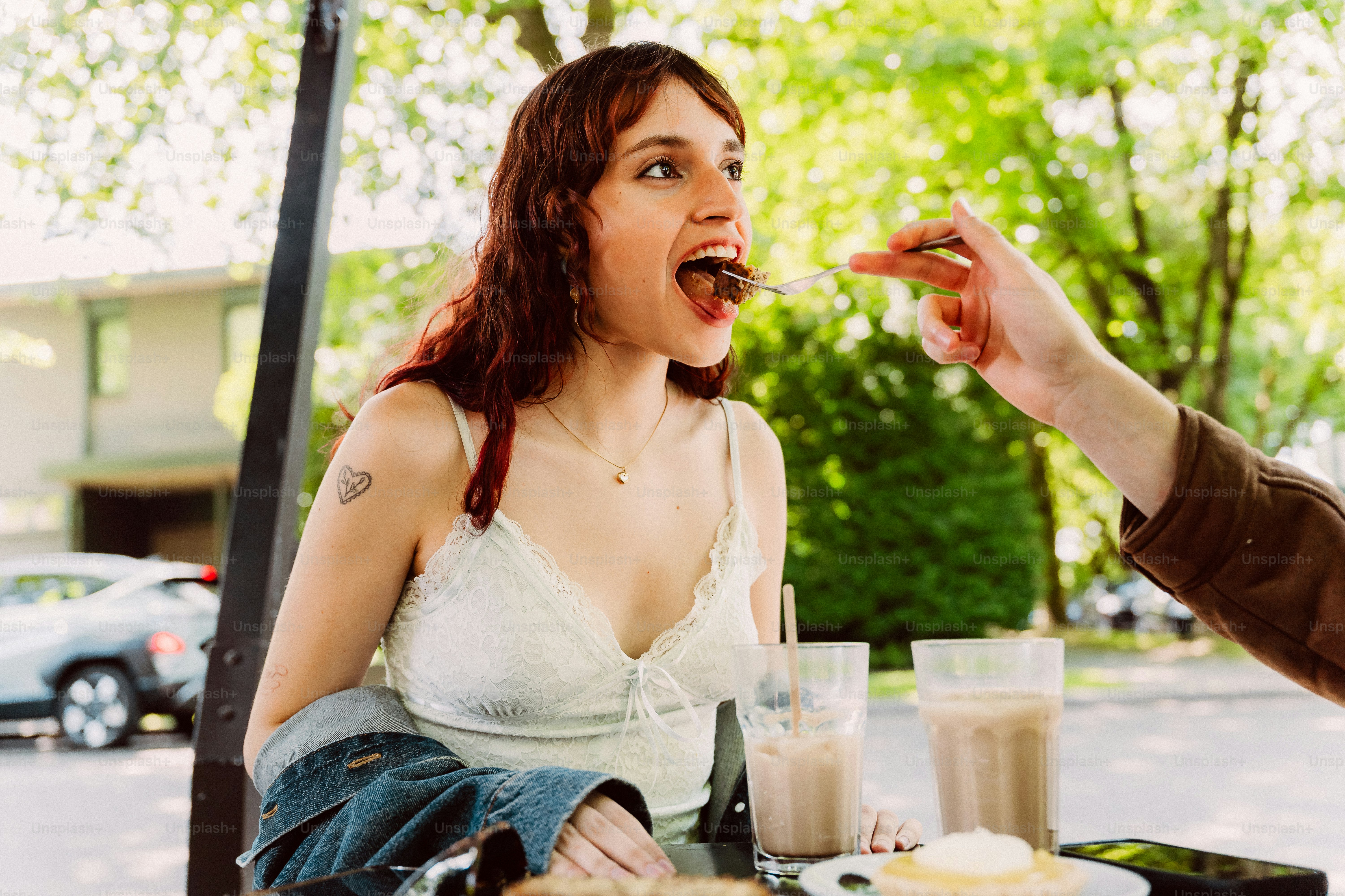 Woman being fed a berry by hand outdoors