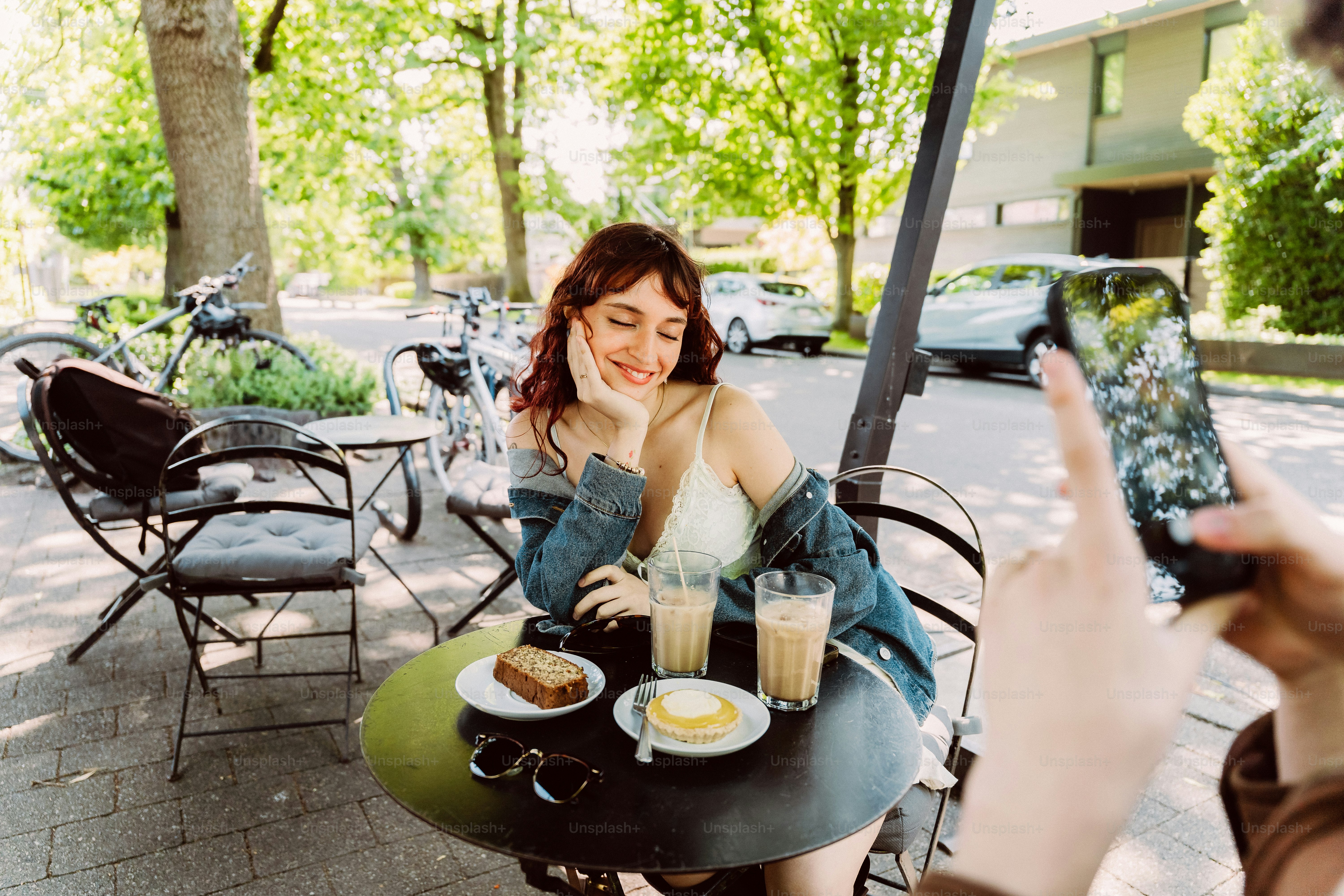 Woman smiling for smartphone picture at outdoor cafe
