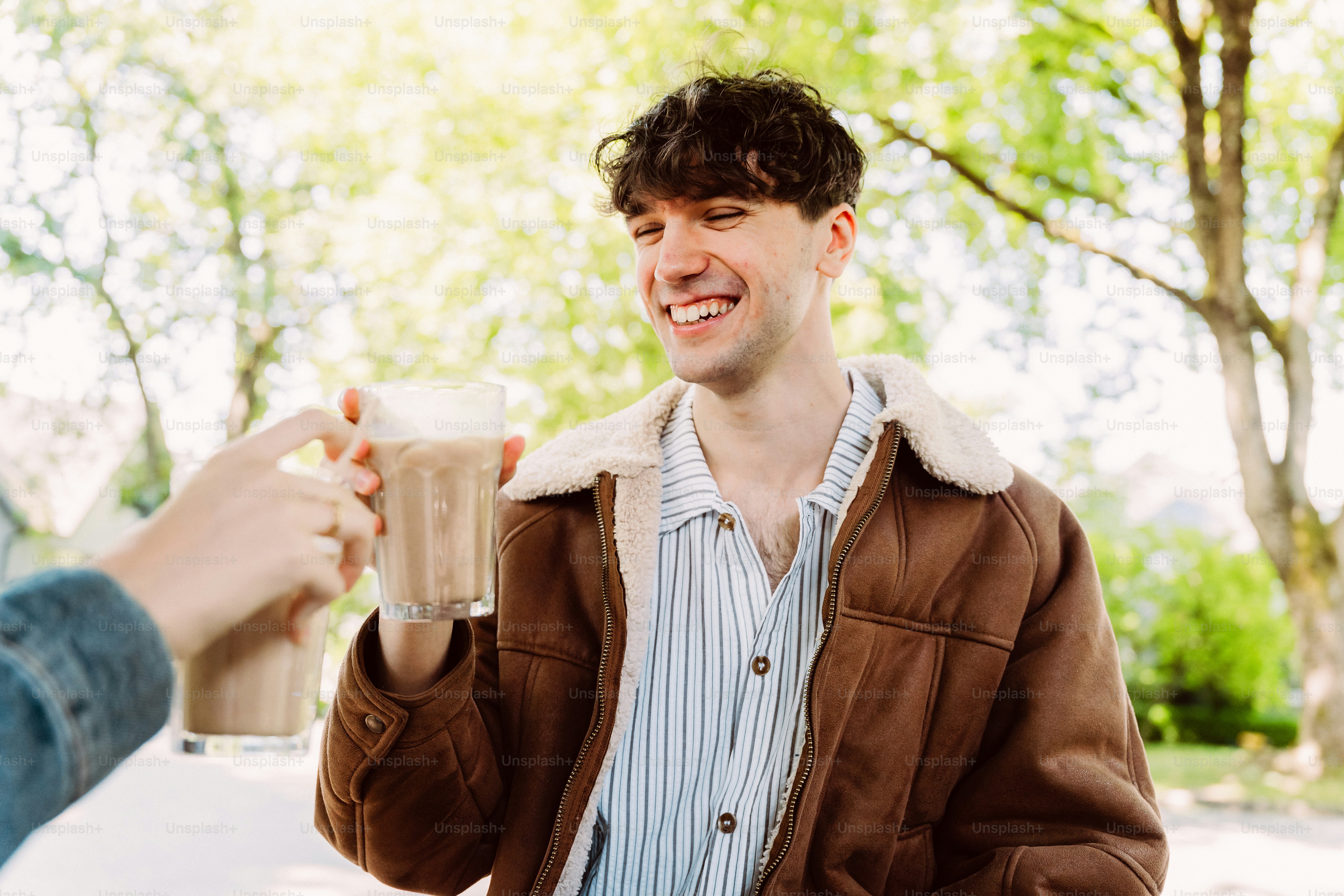 Young man smiling, clinking drinks outdoors