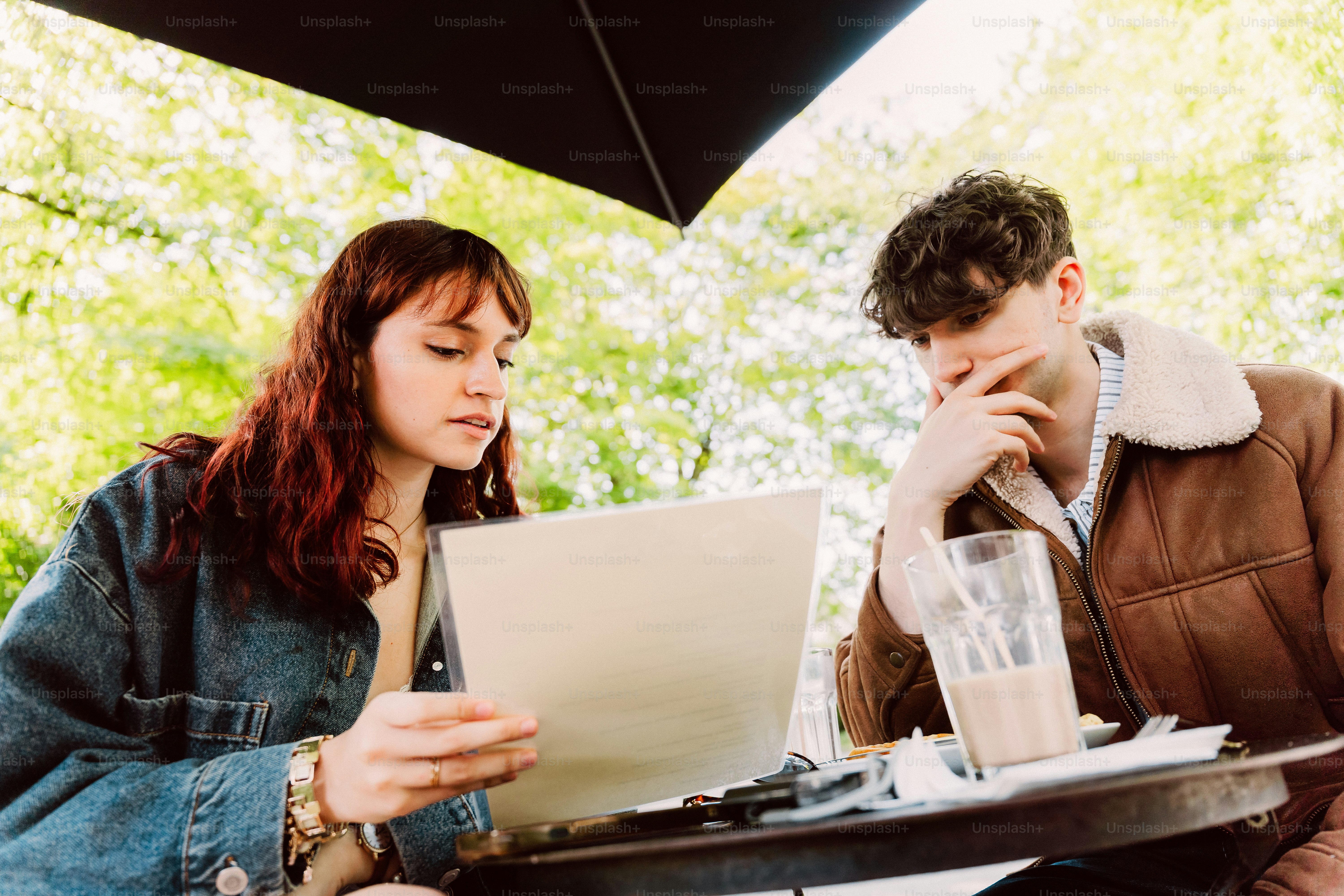 Woman showing man document at outdoor cafe