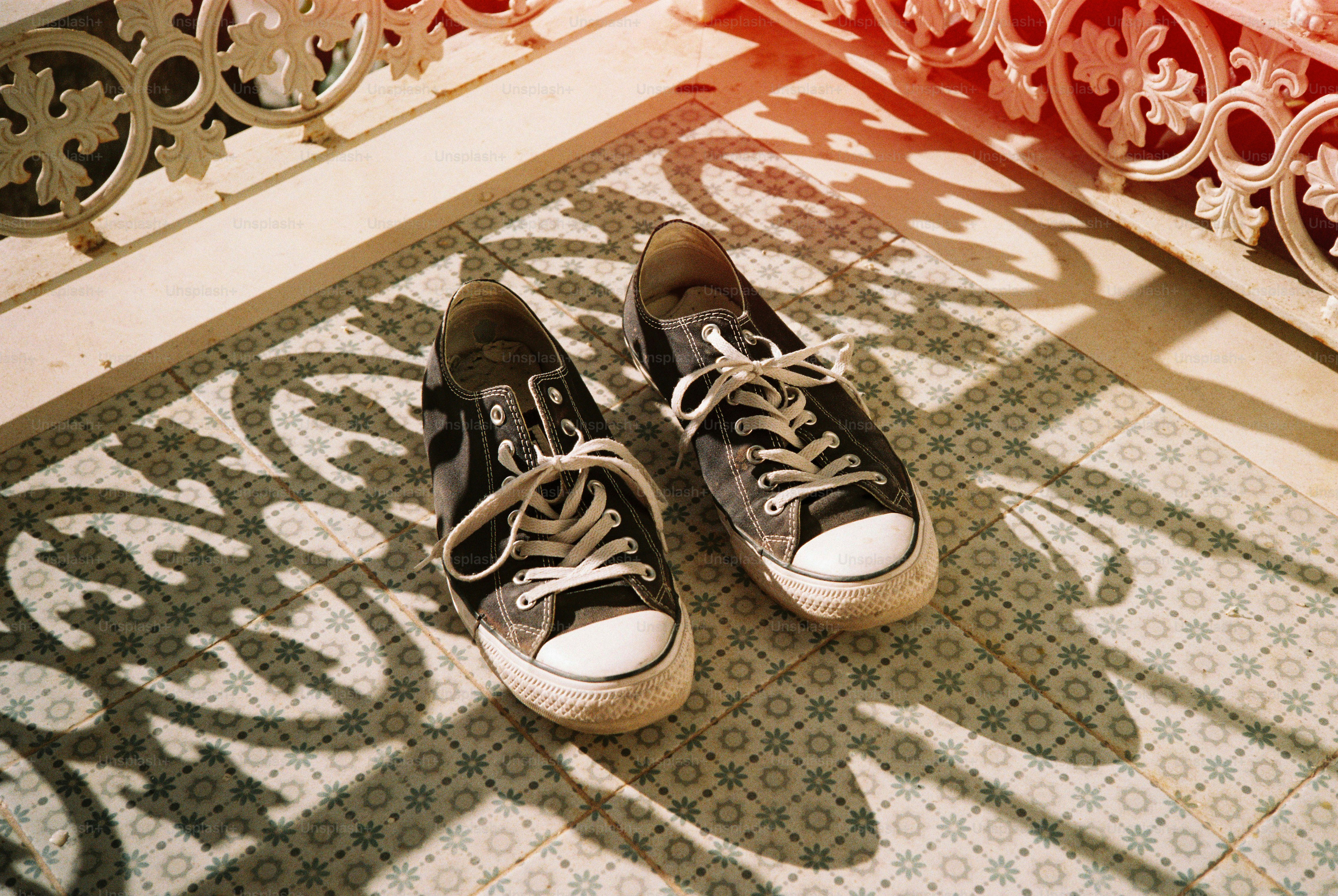 Worn sneakers on sunny tiled balcony with light leak